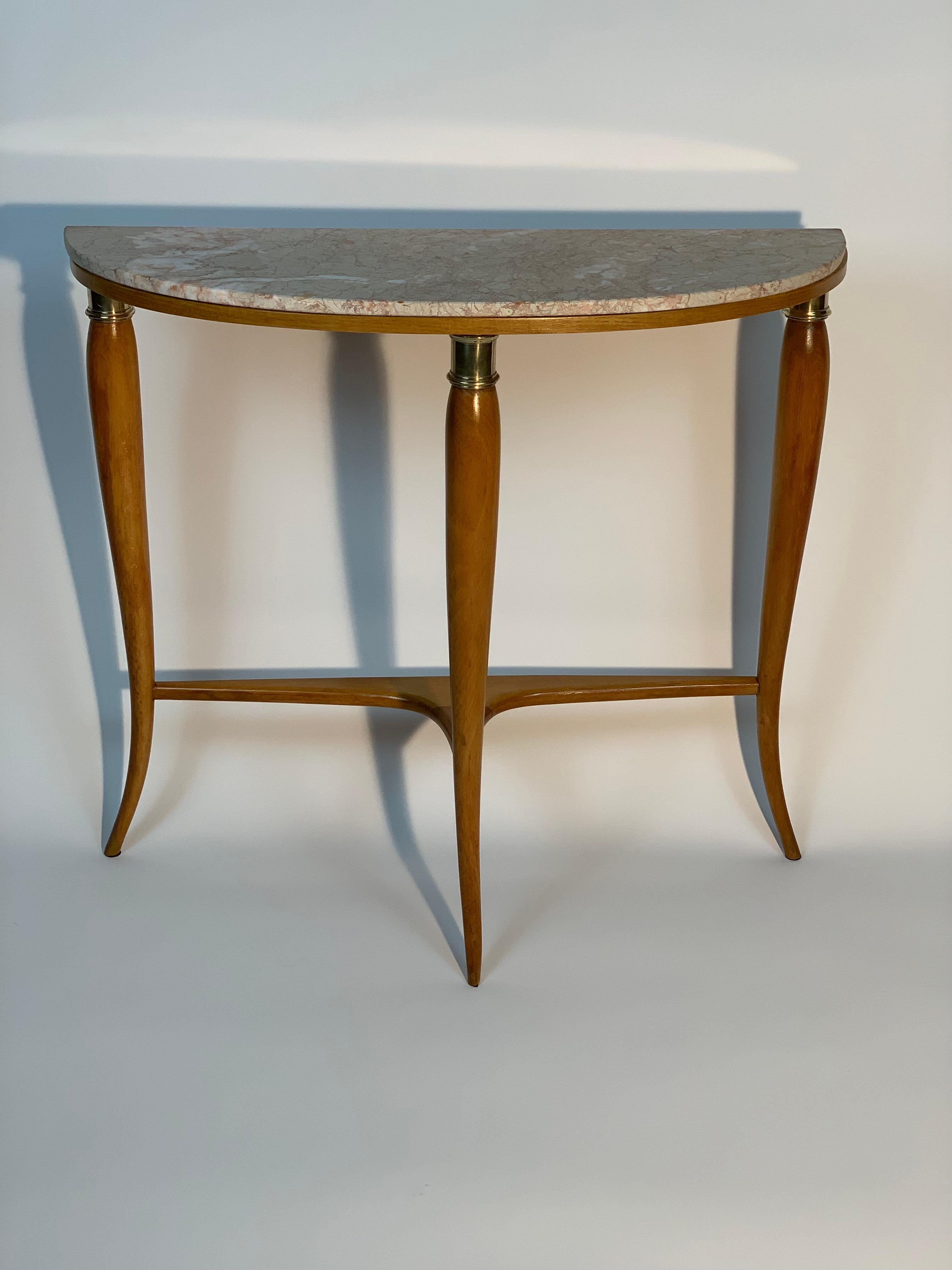Slender Mid Century Italian half moon console table made by the Dassi Lissone Milano company with three tapered sculpted solid wood legs that tighten downwards and end at the top with a sort of capital / crown in cast brass.
The legs are joined by