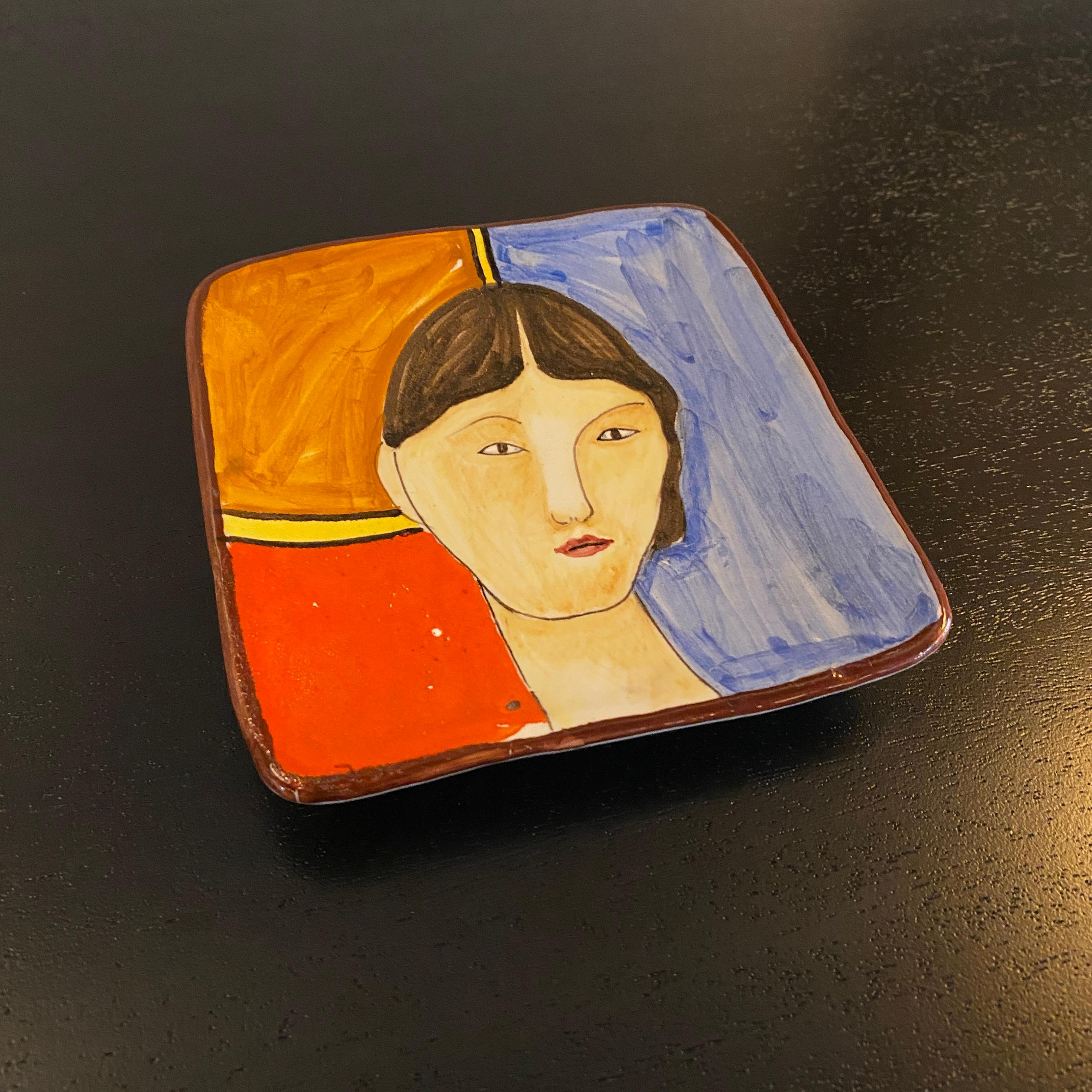 Lovely, Italian mid century modern, hand painted ceramic, pin tray, ring holder or decorative dish by Santucci Deruta features a female portrait against a color-block background of blue, red and orange. It's a playful accent that brings a bright pop