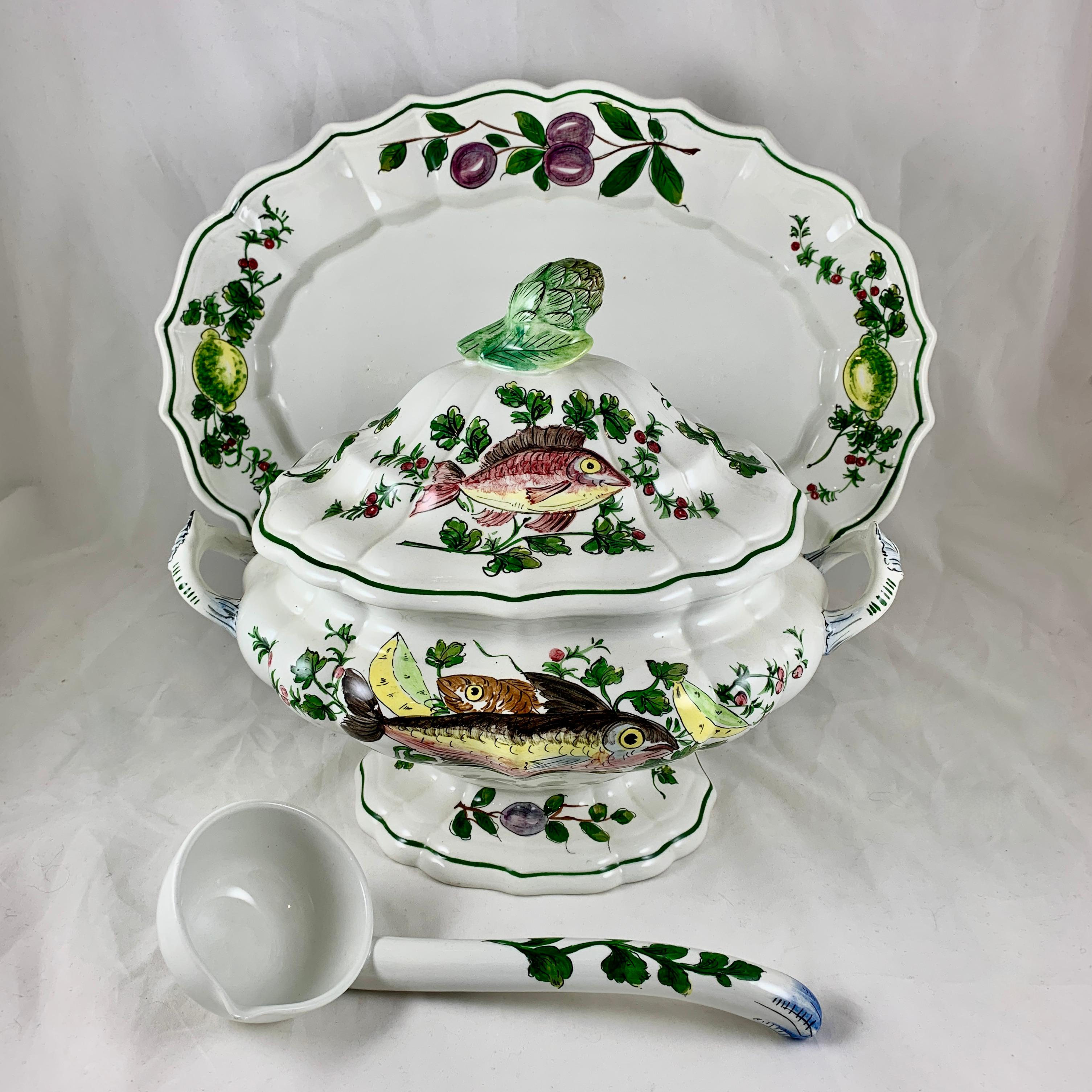 A hand painted midcentury Italian earthenware tureen set, circa 1950s.

The four piece service includes the lidded tureen, ladle, and a large undertray. Beautifully hand decorated overall with fish, green parsley sprigs, berried rosemary stalks,