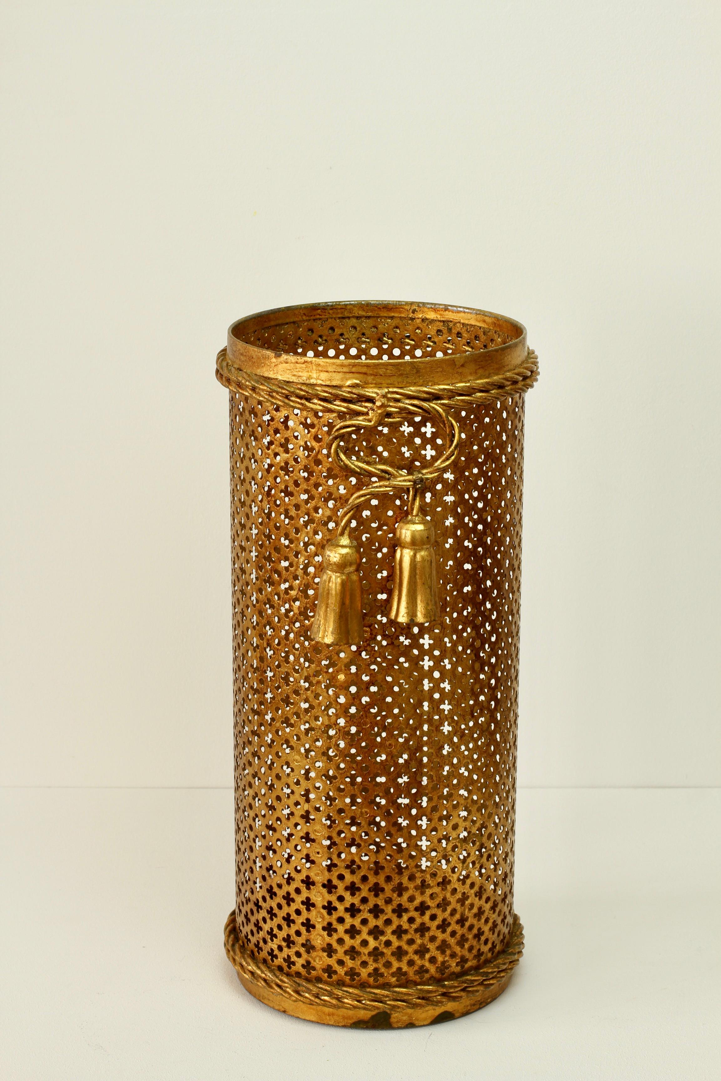 Superbe porte-parapluies de style Hollywood Regency en or, doré et doré du milieu du siècle dernier, fabriqué en Italie, vers 1950. Le travail du métal en forme de treillis perforé, avec des détails de corde pliée et de glands, termine parfaitement