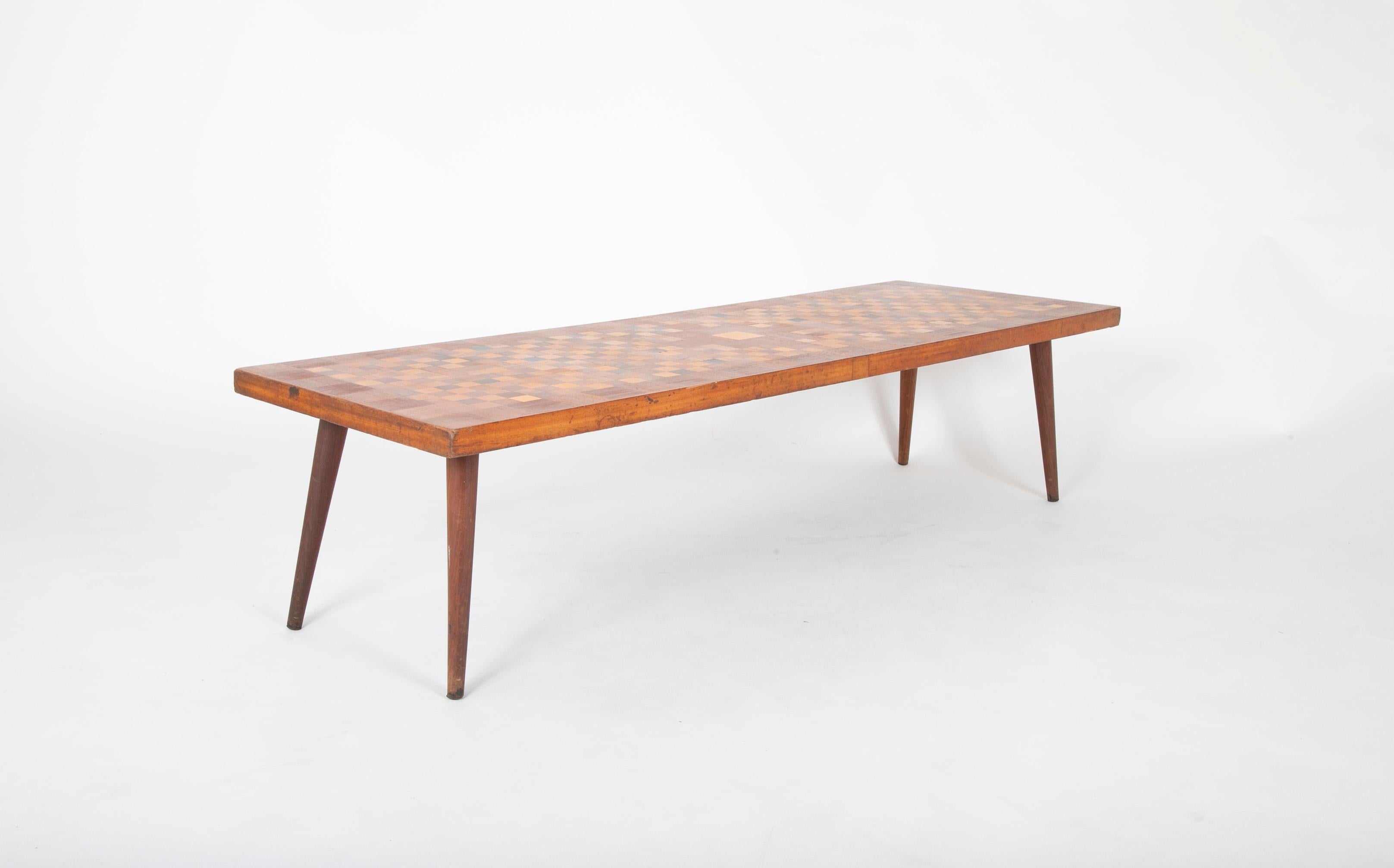 Italian 1960s coffee table with exquisite checkerboard marquetry inlay of various woods. The geometric patterns and spare profile are the height of modernism.