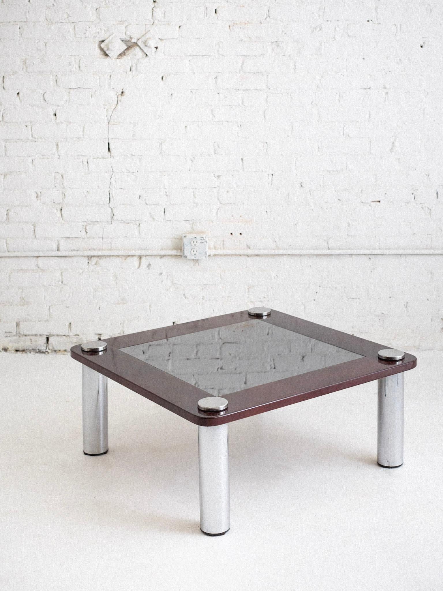 Une table basse italienne de l'ère spatiale. Le bois laqué rouge foncé entoure une surface miroir en verre fumé et des pieds piliers chromés. Provenance : Florence, Italie. 