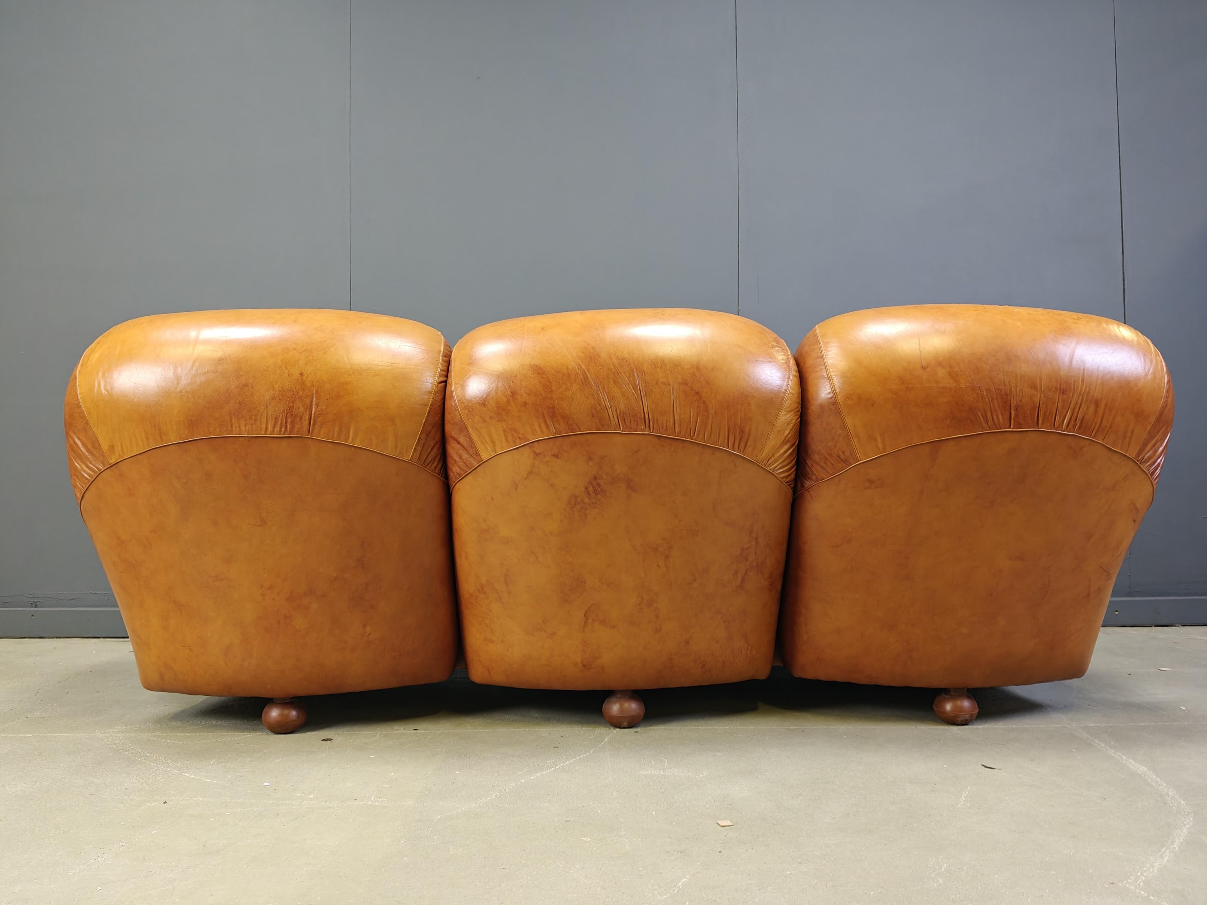Canapé 3 places en cuir cognac du milieu du siècle, magnifiquement réalisé et très, très confortable.

Le canapé est doté d'un détail en cuir plié très cool à l'avant, sur les assises et sur les dossiers.

De dos également, ce canapé n'est pas un