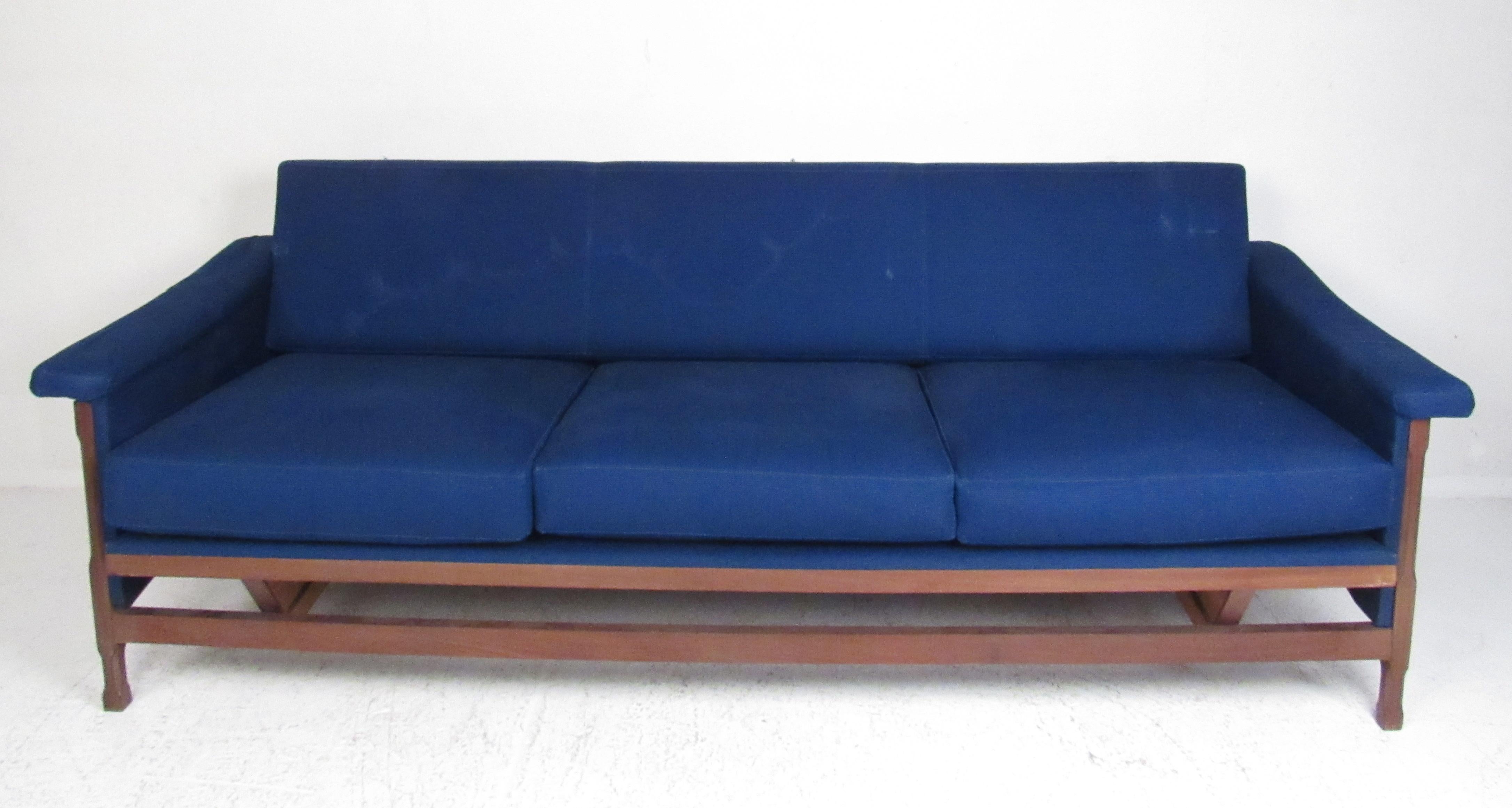 Dieses atemberaubende Set im modernen Vintage-Stil besteht aus zwei Sesseln und einem dreisitzigen Sofa. Der geschnitzte Nussbaumrahmen, die geflügelten Armlehnen und die königsblaue Polsterung unterstreichen den Midcentury-Charme. Dieses elegante