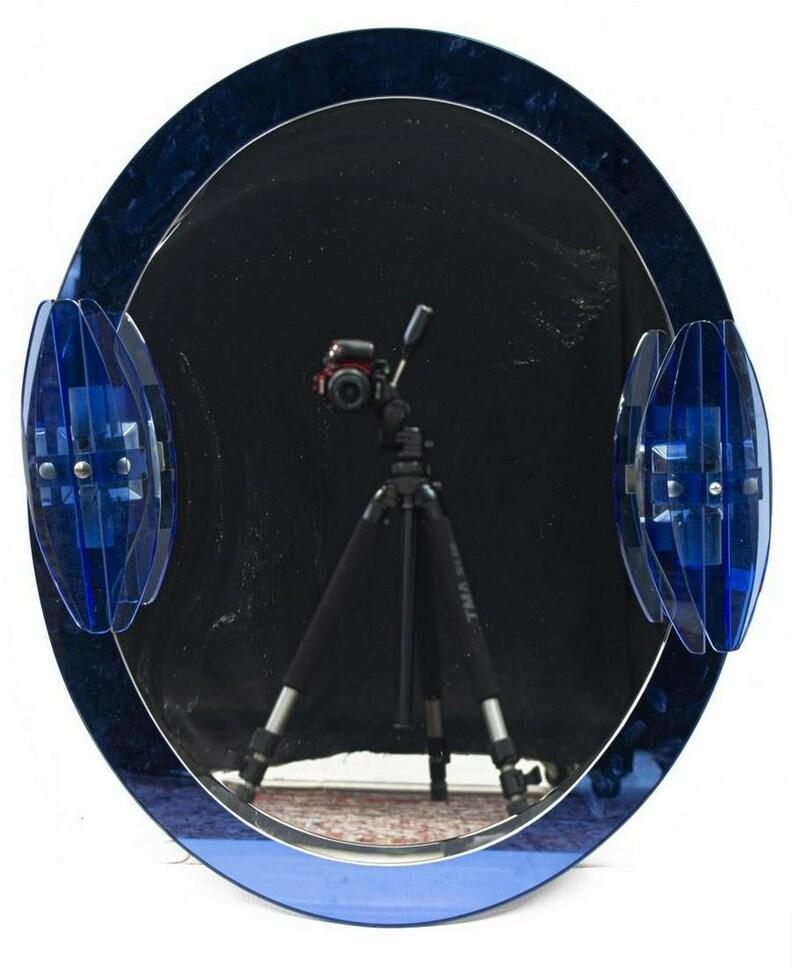 A stunning Italian Modernist blue glass bathroom vanity set by LUPI Cristal-Luxor. The fabulous Art Deco and Hollywood Regency influenced vintage set comprising an oval shaped beveled mirror with sapphire blue colored glass surround, the mirror