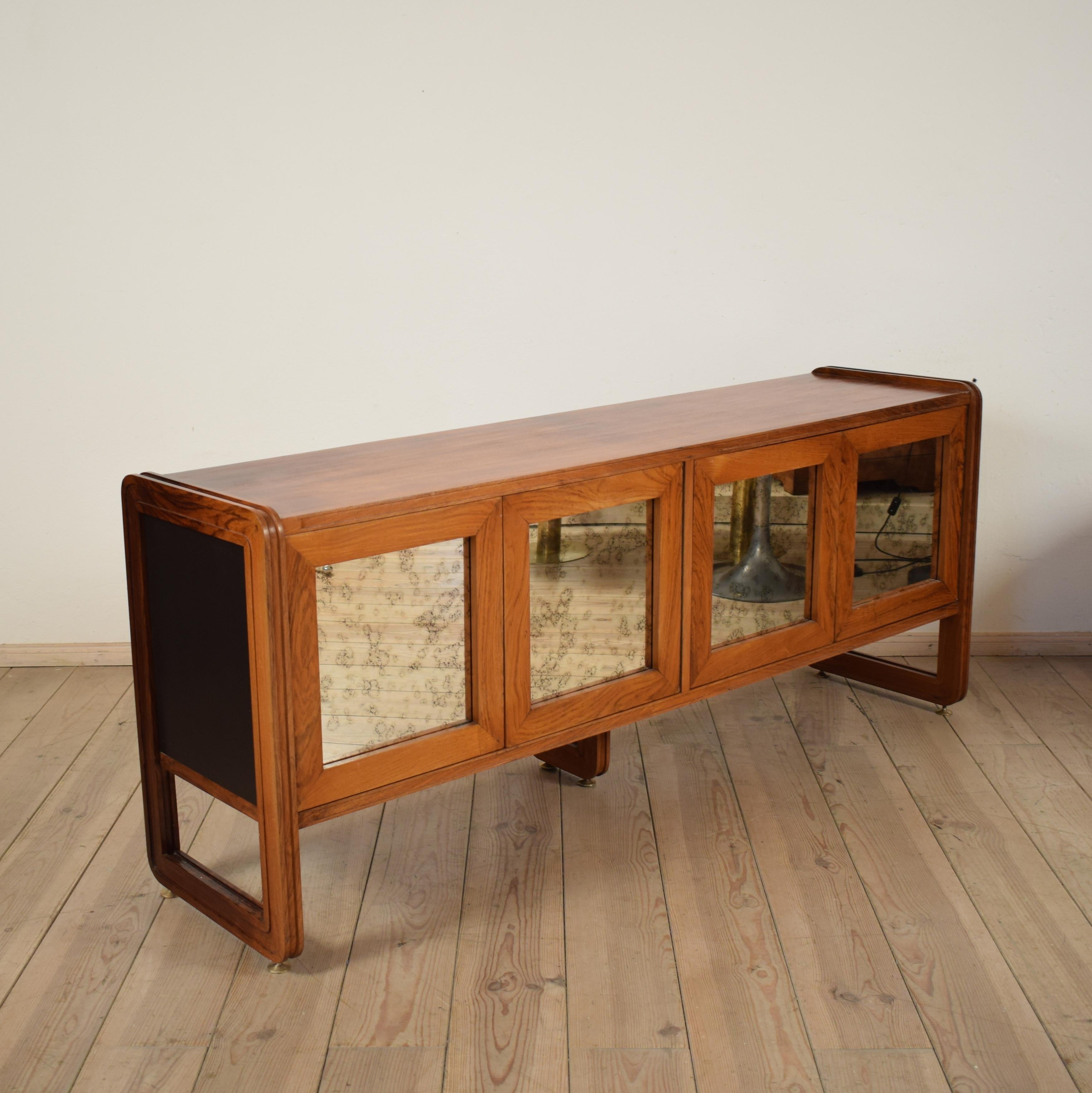 This elegant and beautiful Italian sideboard was designed and produced in the 1960s probably by Salocchi.
It has a solid hardwood (probably mahogany) frame with black lacquered inlays on the sides and from the inside. There are mirror inlets in the