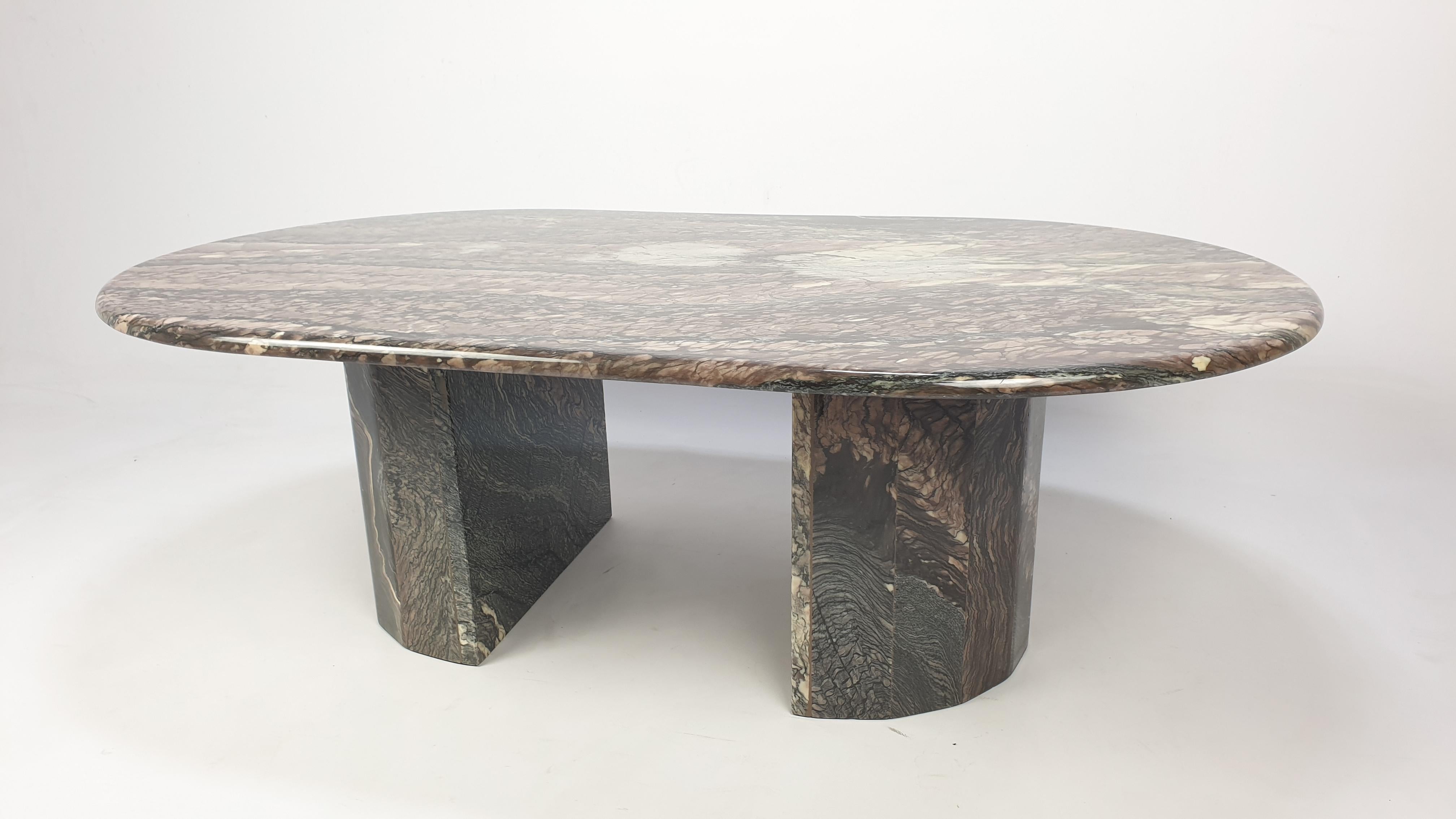 An exceptional Italian coffee table handcrafted out of marble. The fabulous marble features a beautiful wave pattern of different colors. The oval top is rounded on the edge. The round base is made of two separate pieces and can be placed in