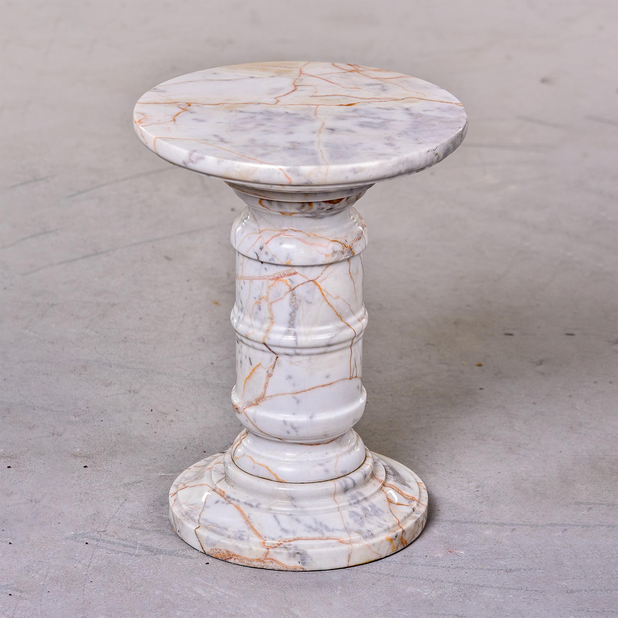 Circa 1970s small Italian marble table or stand with turned pedestal base and round top. Marble is white with streaks of gray and apricot. Multiple tables in this marble and style are available at the time of this posting. Sizes may vary slightly.