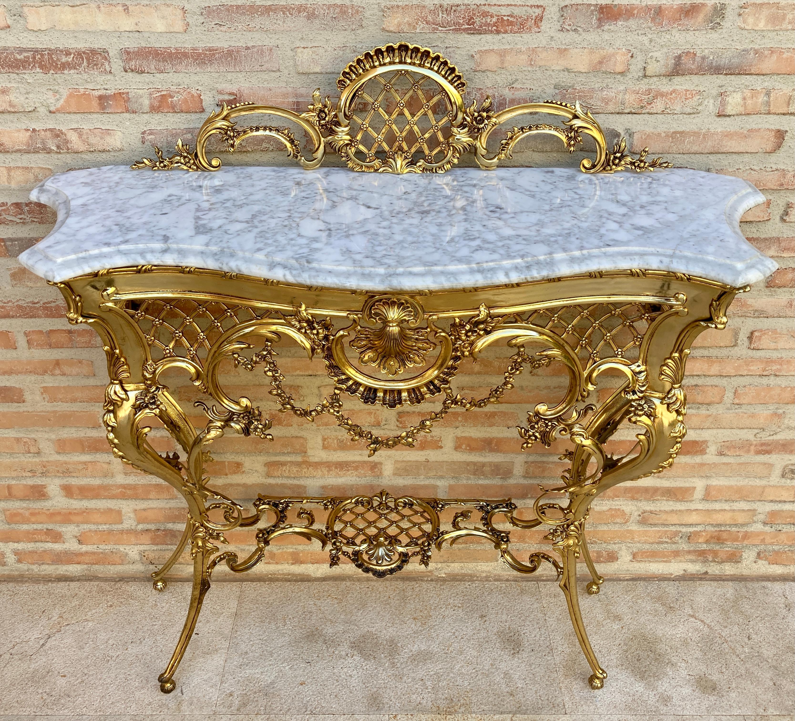 Italian mid-century marble top and bronze console 
This 1960s Italian console table has a brass frame with cornucopia and heraldic motif. The top is marble. 
Italian mid-century console with a sloping bronze frame and marble top.