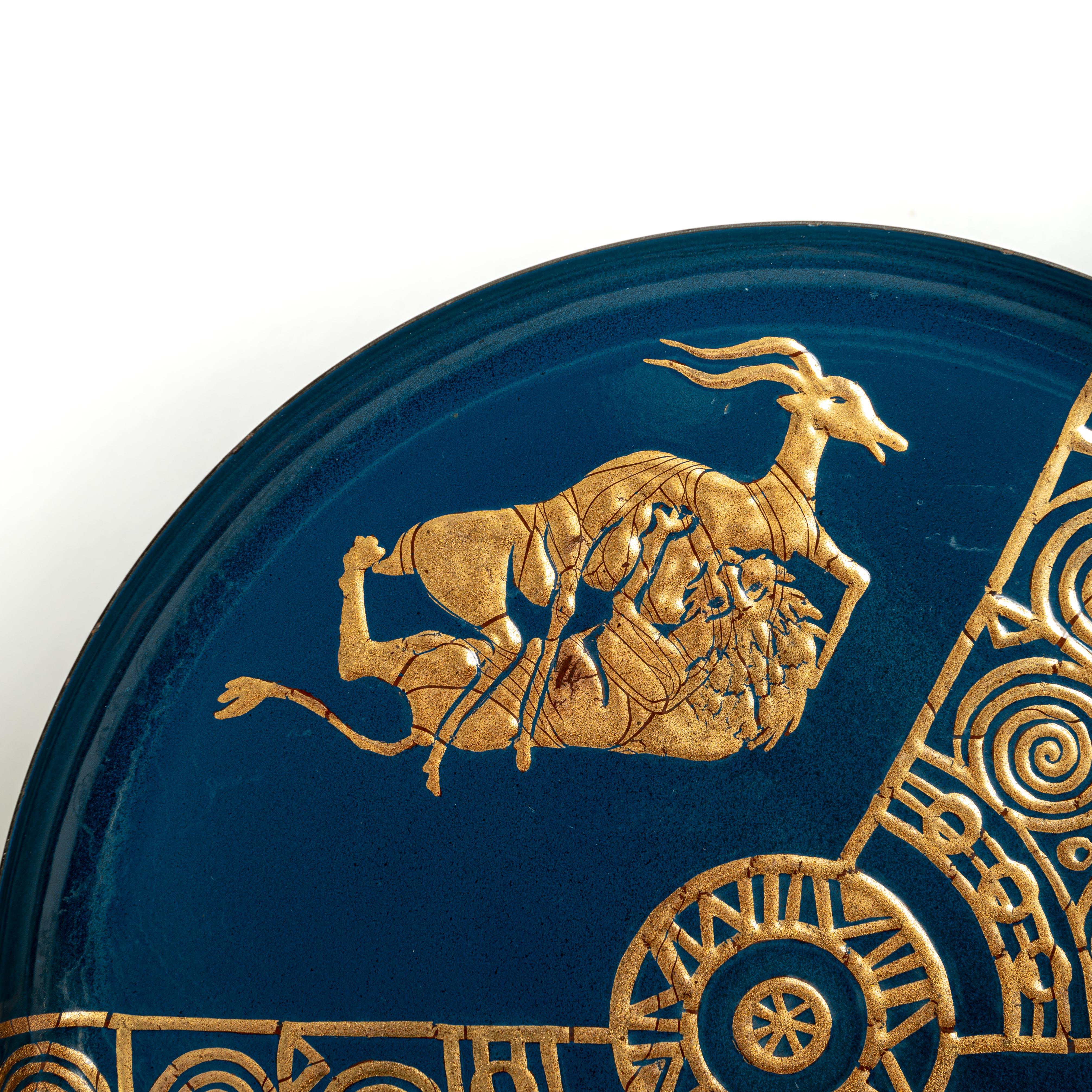 Extremely decorative and rare metal tray from the 50s Italy. 
The turquoise-blue base color is decorated with a gilded representation of classicism (stylized) and decorative elements. 
The fight scene of lion with gazelle is applied with 2 different