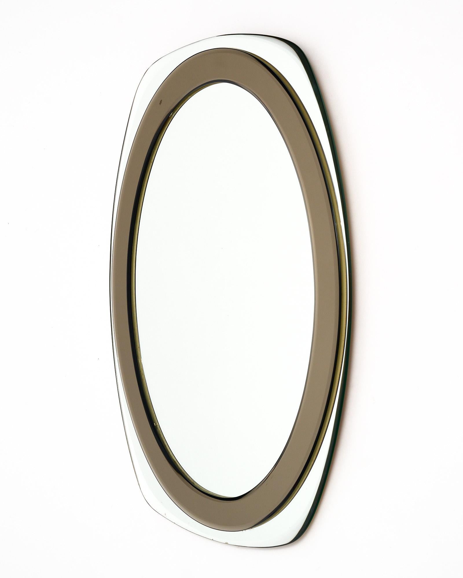 Mirror from Mid-Century Italy with an exterior beveled mirror frame, a middle smoked glass beveled frame, and central oval mirror. This piece is all original and perfect for a powder room or entryway.
