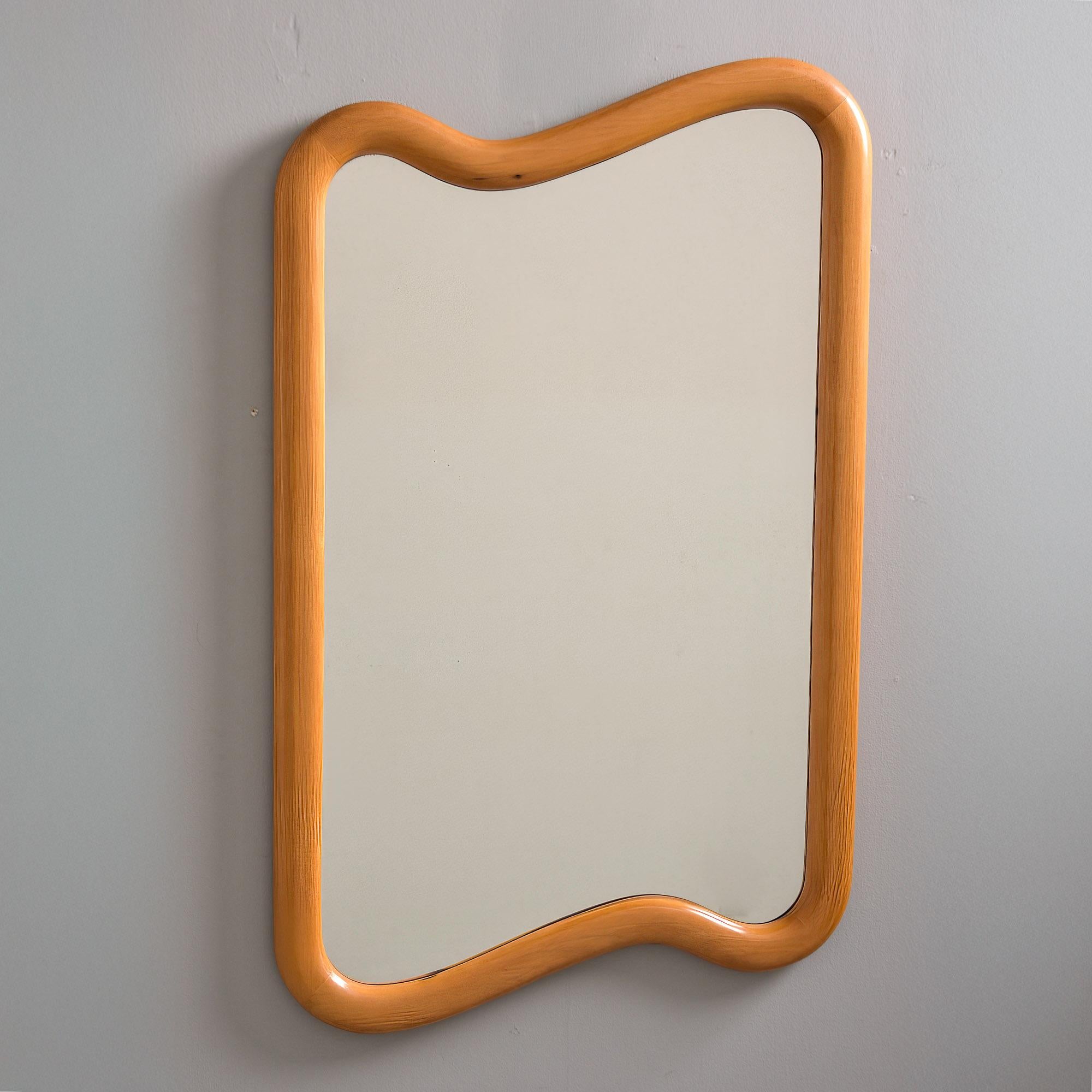 Trouvé en Italie, ce miroir de forme biomorphique date de la fin des années 1960 - début des années 1970. Grand cadre de miroir rectangulaire irrégulier et incurvé qui semble être en érable ou en hêtre teinté. Fabricant inconnu. Très bon état