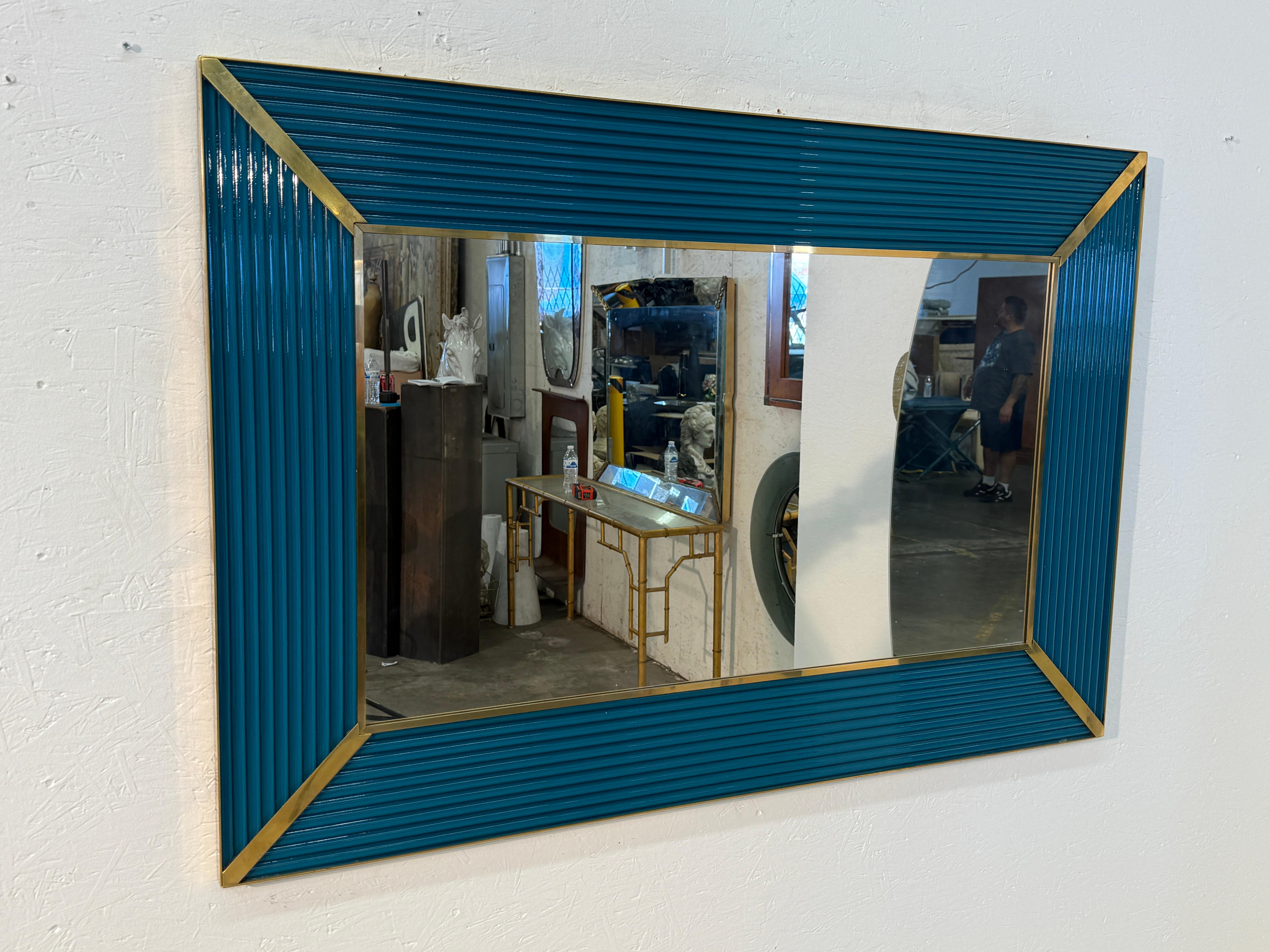 This mid-century Italian mirror presents a bold yet refined aesthetic, ideal for adding character to an interior. Its rectangular shape is framed with ribbed teal panels, creating a sense of depth and movement. The corners are accentuated with