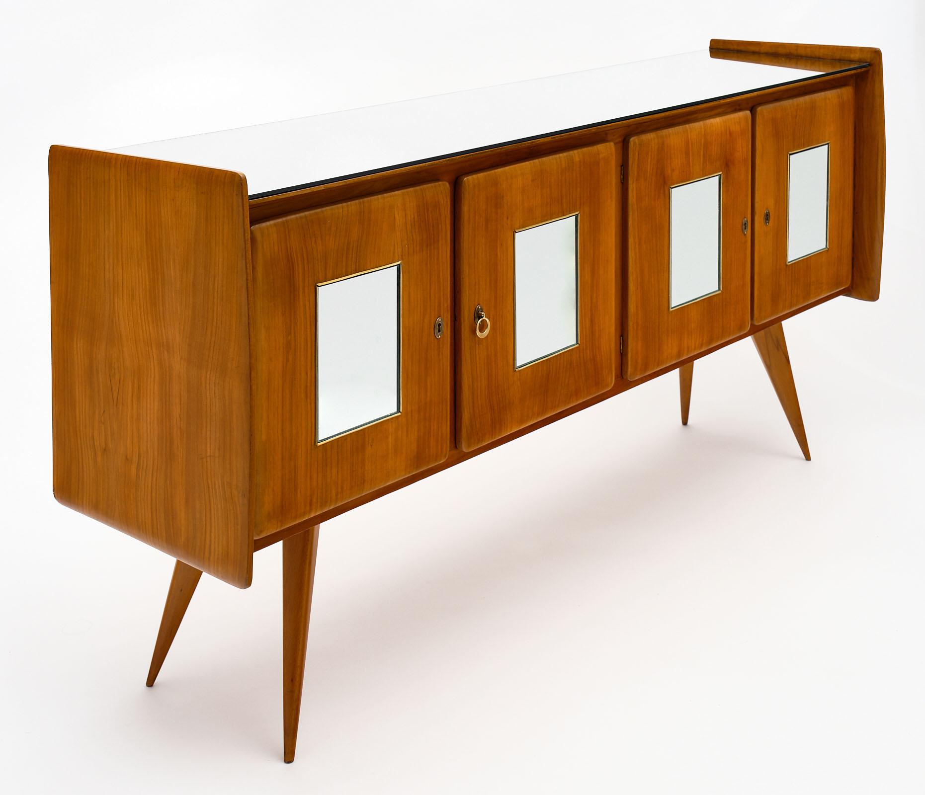 Midcentury Italian mirrored buffet made of solid cherrywood in the style of Paolo Buffa. We love the mirrored top and mirrored center panels on all four doors. The tapered; flared legs add midcentury lines to this superb piece.