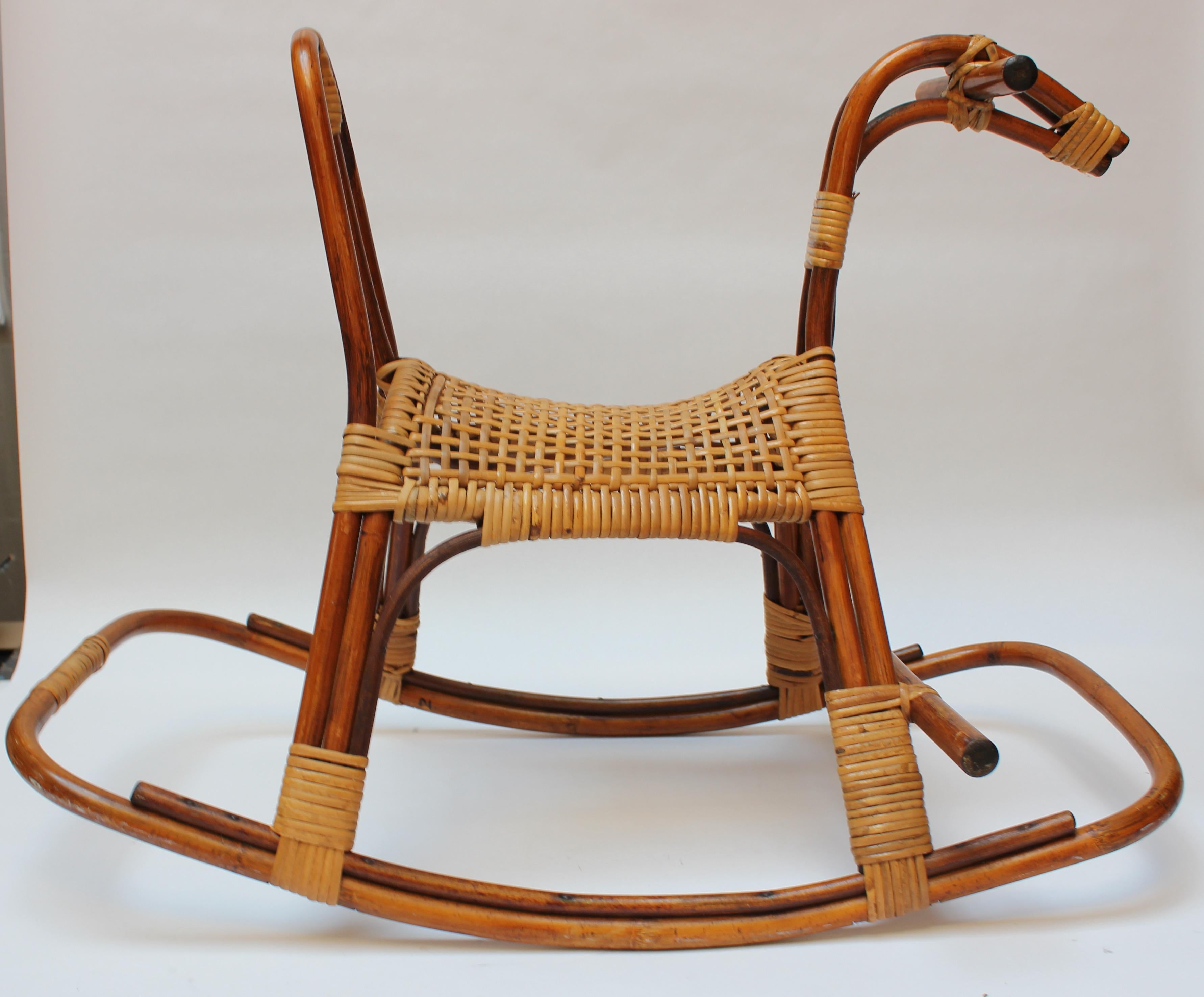 Mid-century rocking horse, often attributed to France Albini, composed of a bamboo frame with woven rattan seat and accents. 
Very good, vintage condition with natural patina and light wear (slight discoloration to bamboo and scuffs present, as
