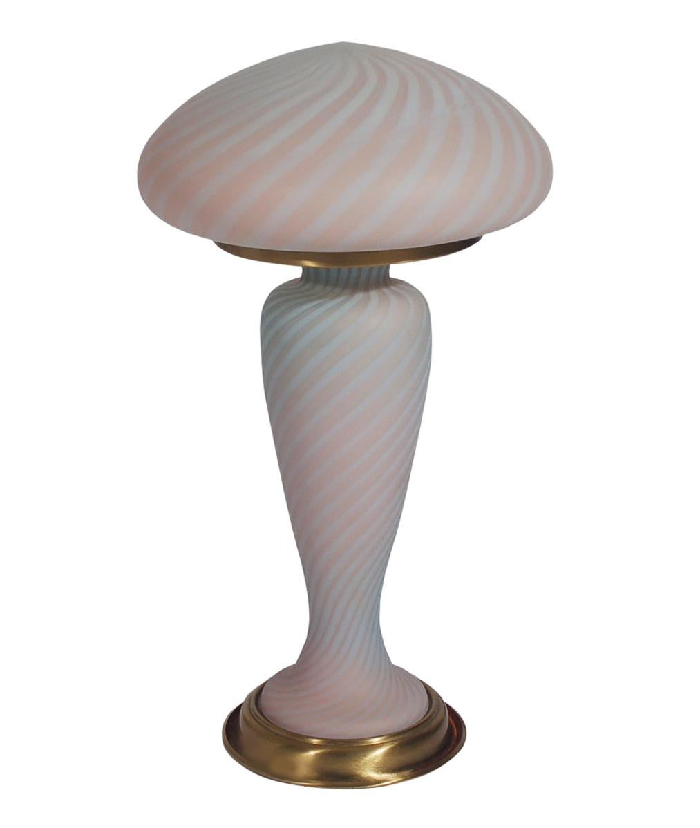 A vintage art glass lamp from Italy circa 1950s attributed to Murano. It features a two part swirled art glass design with brass details. Tested and working.