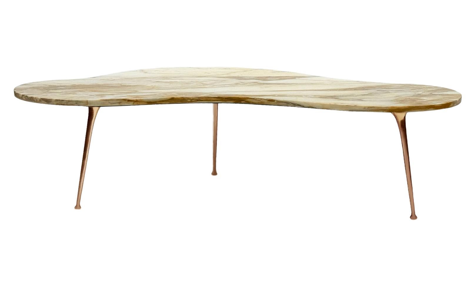 Une superbe table basse italienne datant des années 1960. Elle se caractérise par une forme libre irrégulière.  Plateau de forme rein en marbre beige, avec des pieds sexy en laiton.