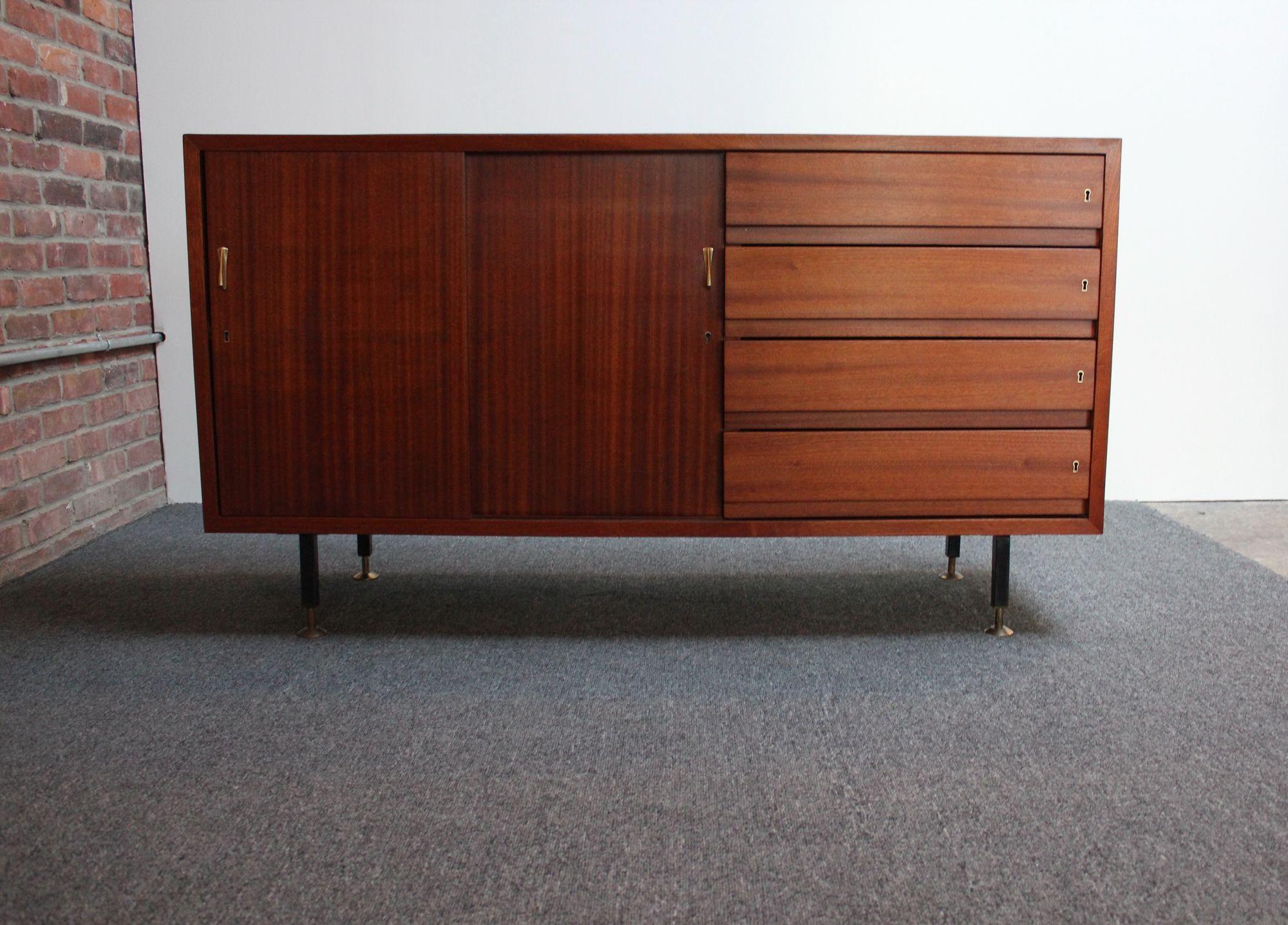 Vintage Italian credenza in mahogany with sky blue laminate surface, sculpted brass pulls, and adjustable brass feet (ca. 1960s, Italy). 
Composed of four locking drawers and two sliding doors that open to reveal open storage flanked by a single