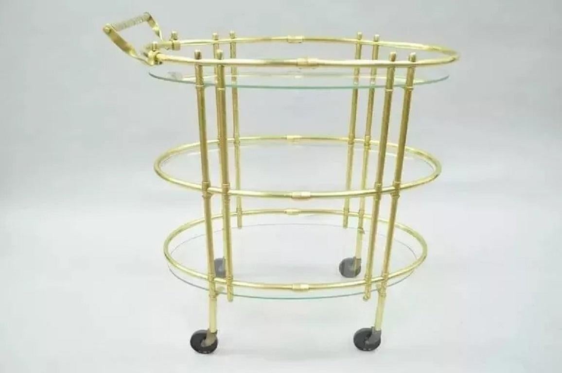 Chariot à thé ovale à trois étages en laiton poli et verre, de style italien moderne du milieu du siècle dernier. A se caractérise par un cadre en laiton poli, des étagères ovales en verre flottant, des roulettes roulantes, une poignée tournée en