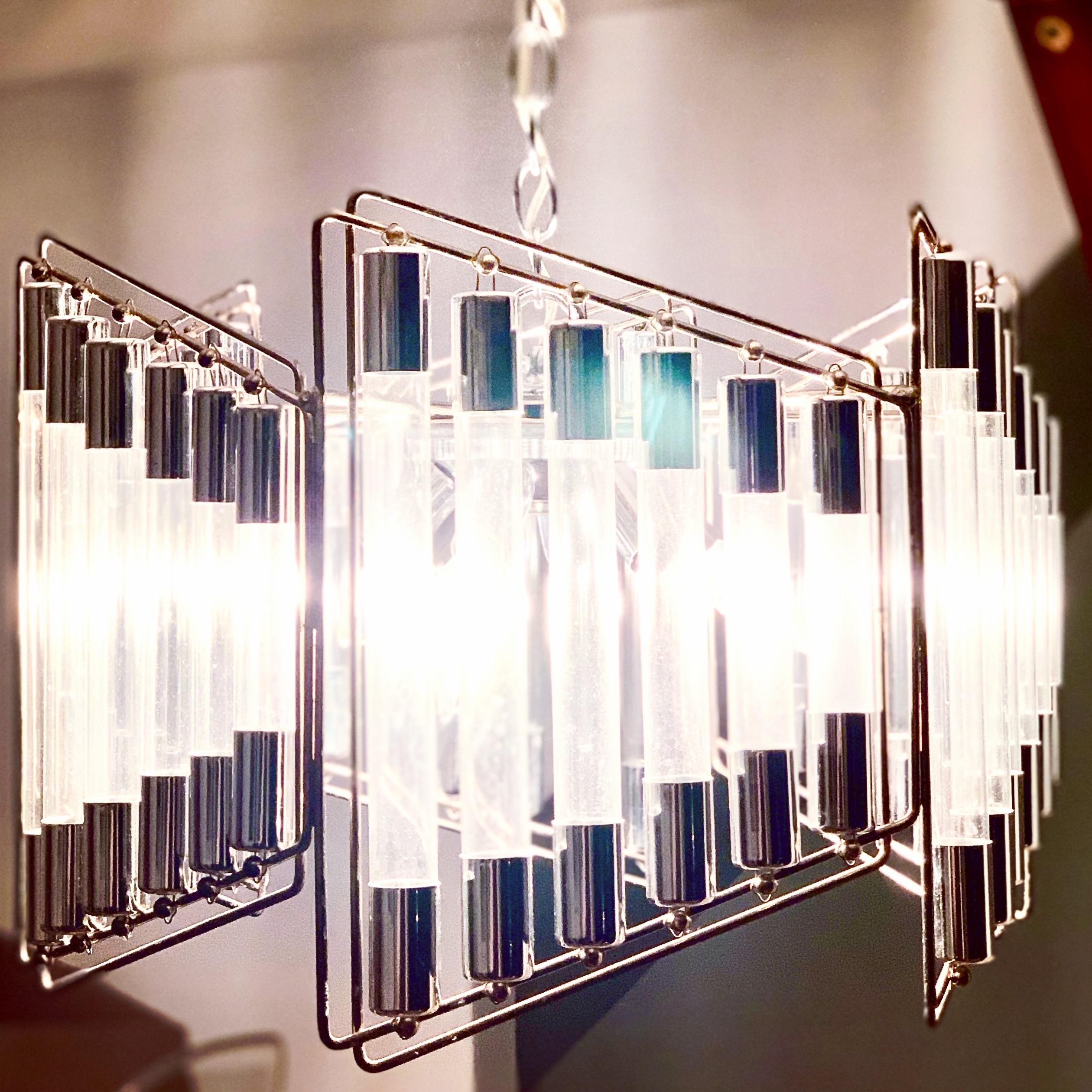 Rare steel and glass Italian modern / Postmodern design. Glass tubes serve to refract and emit light in a gorgeous manner and the trapezoidal ring that holds the tubes echoes around the fixture to create a harmonious yet Space Age, Postmodern design.