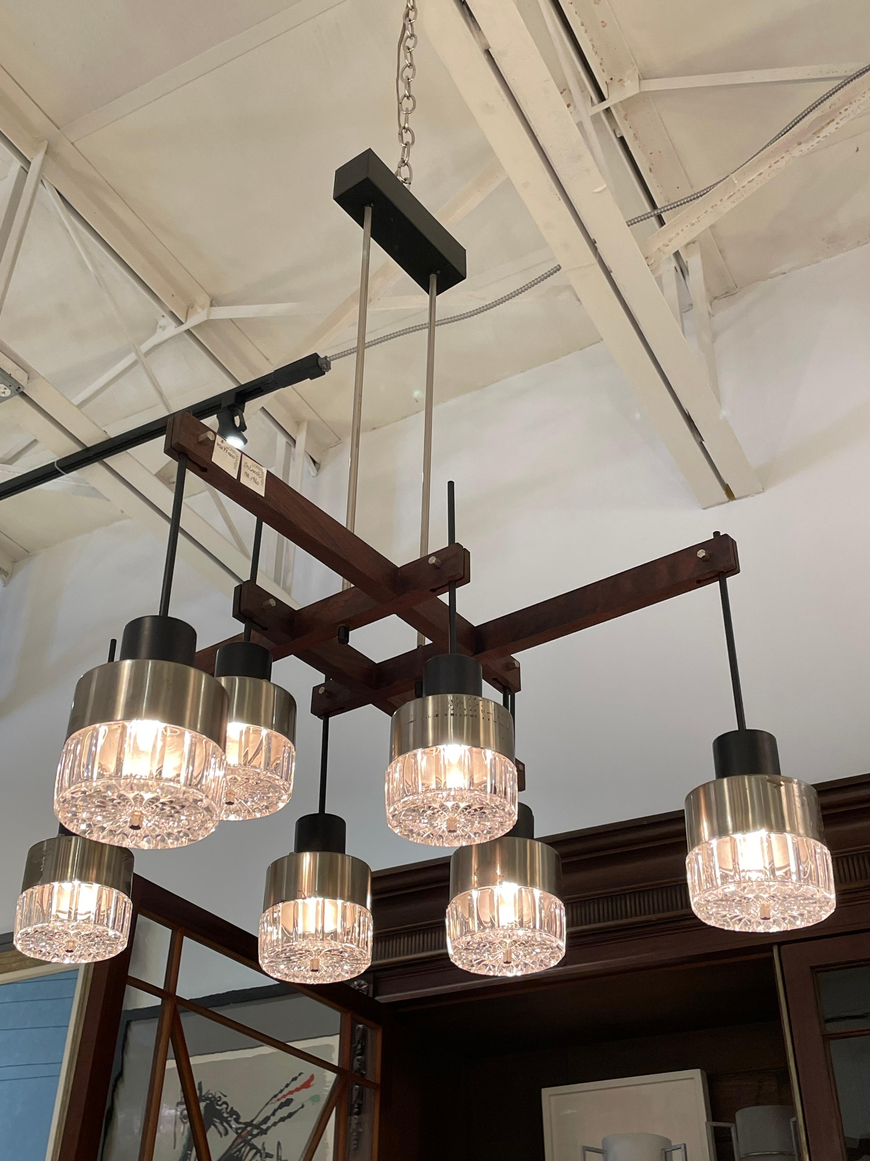 In the style of Stilnovo, this wonderful 8 light glass, walnut and metal chandelier with original canopy is extremely sculptural, geometric and modern for a classic mid-century light.