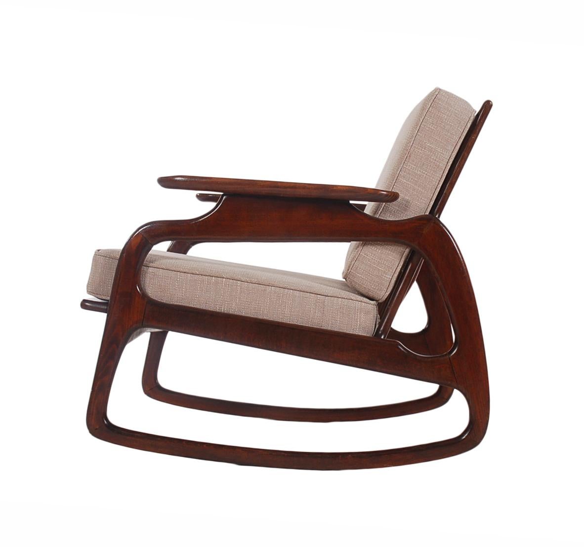 A beautiful and sculptural rocking chair in the style of Gio Ponti. This chair features solid walnut construction and newly upholstered seat cushions. Marked: Made in Italy. Circa 1960's