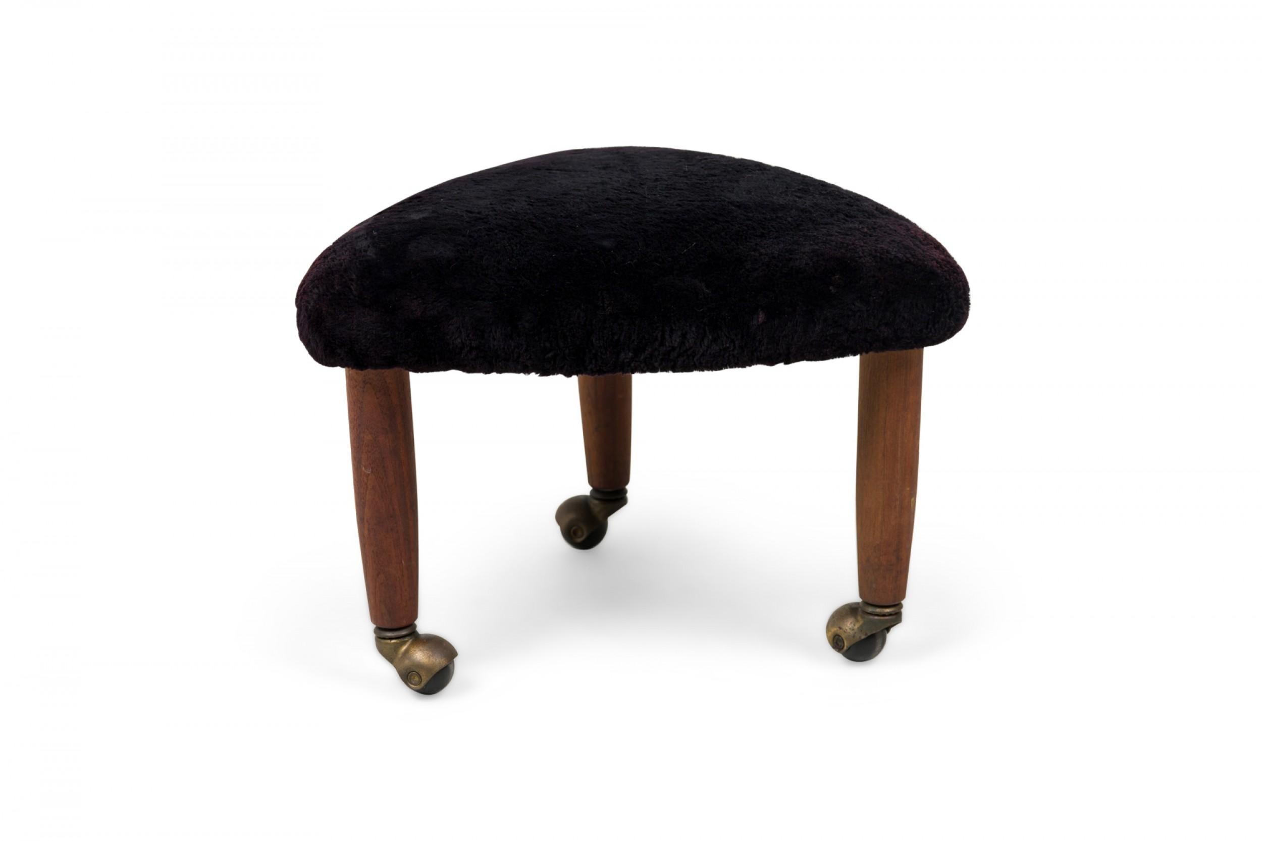 Mid-Century Italian Modern triangular footstool, upholstered in plush black velour, standing on 3 legs with brass casters. (manner of GIO PONTI)(Available in orange: REG4086 as a PAIR)