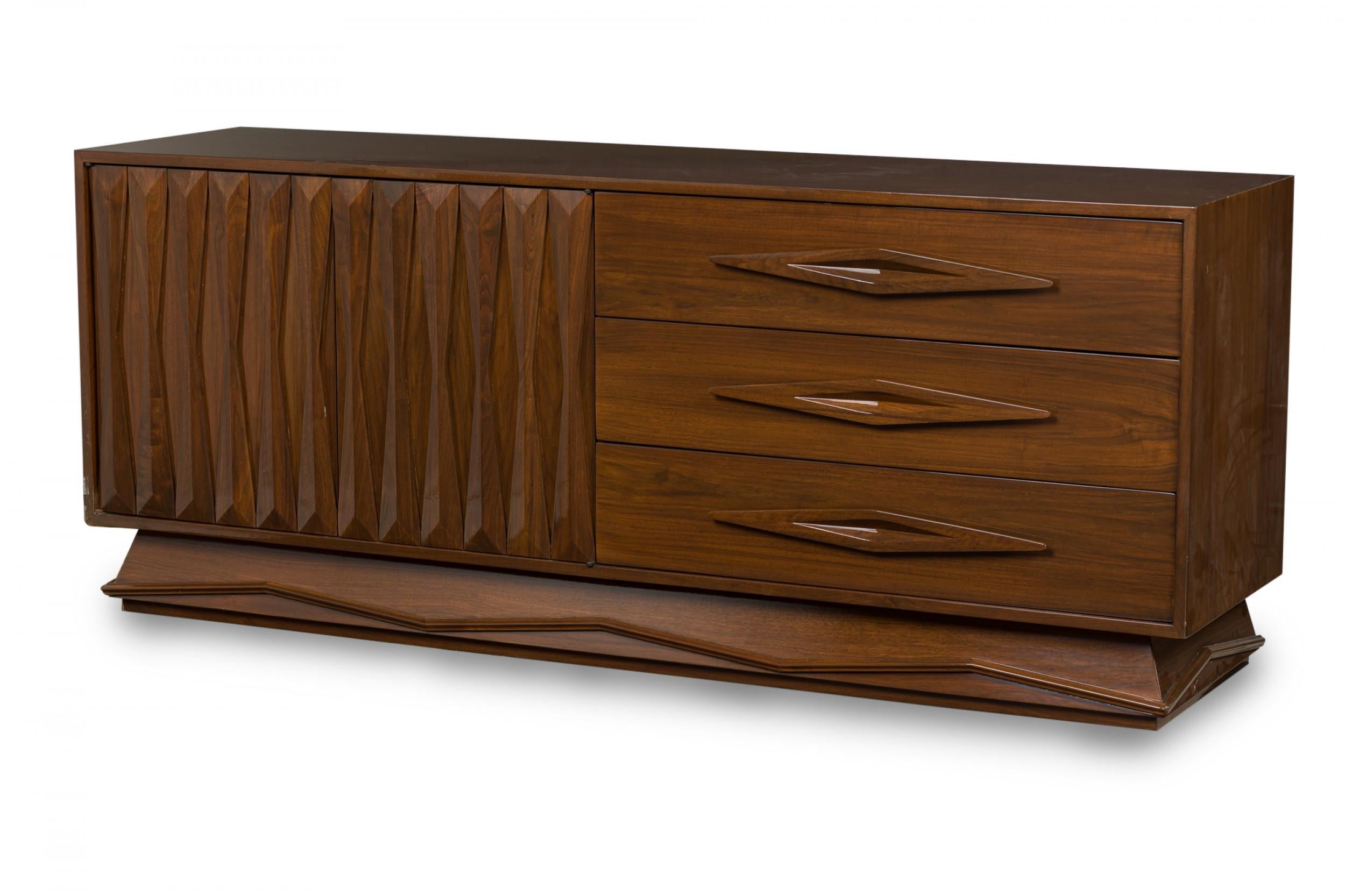 Credenza italiana della metà del secolo in noce laccato con due ante a battente con intagli geometrici a sinistra e tre ampi cassetti con tiretti a diamante allungati intagliati a destra che poggiano su una base trapezoidale con un disegno