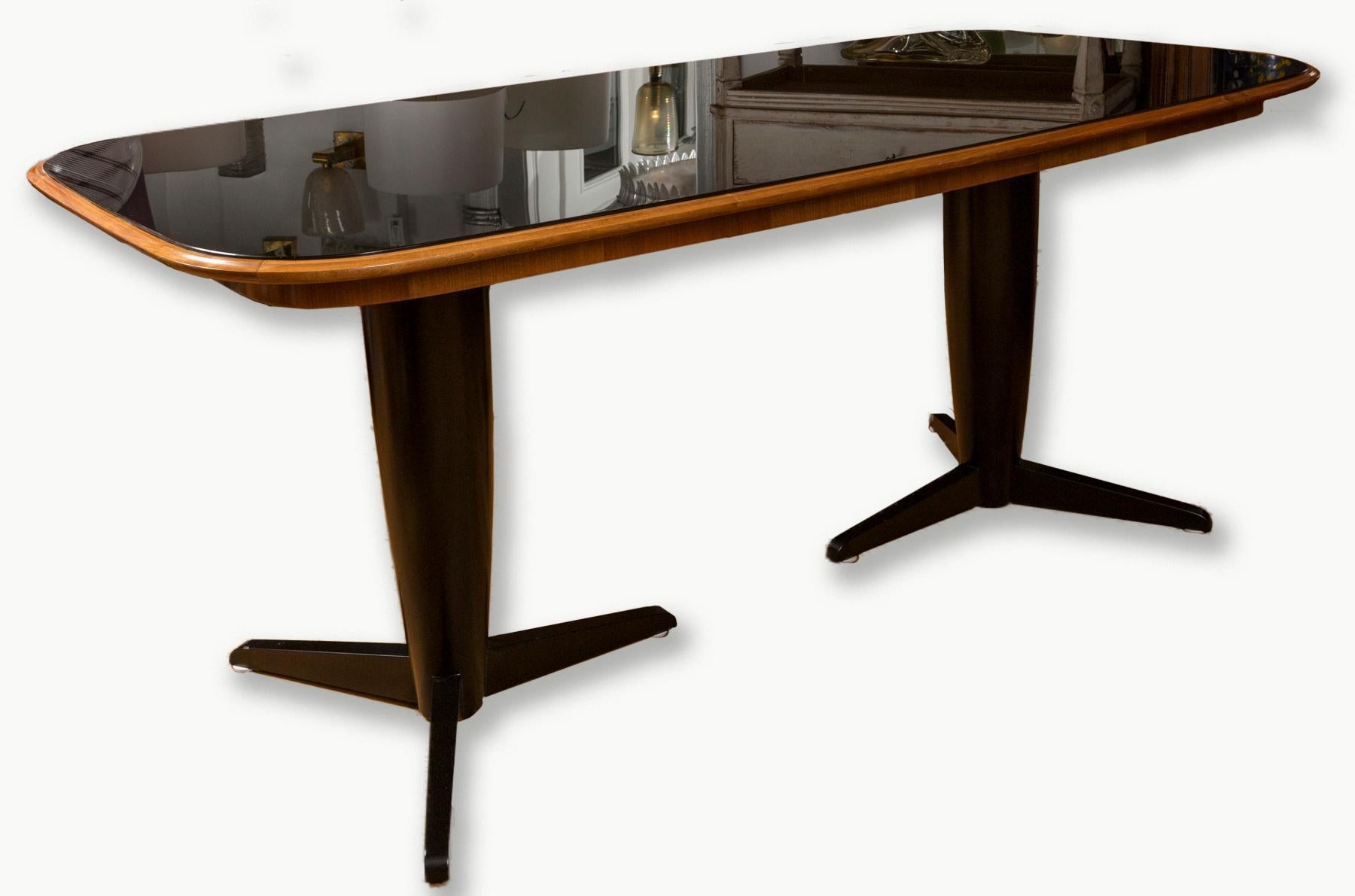 An elegant tapered and curving  rectangular shaped plateau in walnut with inset black glass  above complimenting   matte black lacquered and tapered double pedestal base on tripod feet.
Extremely solid and heavy table base 
Origin: Italy
Dating
