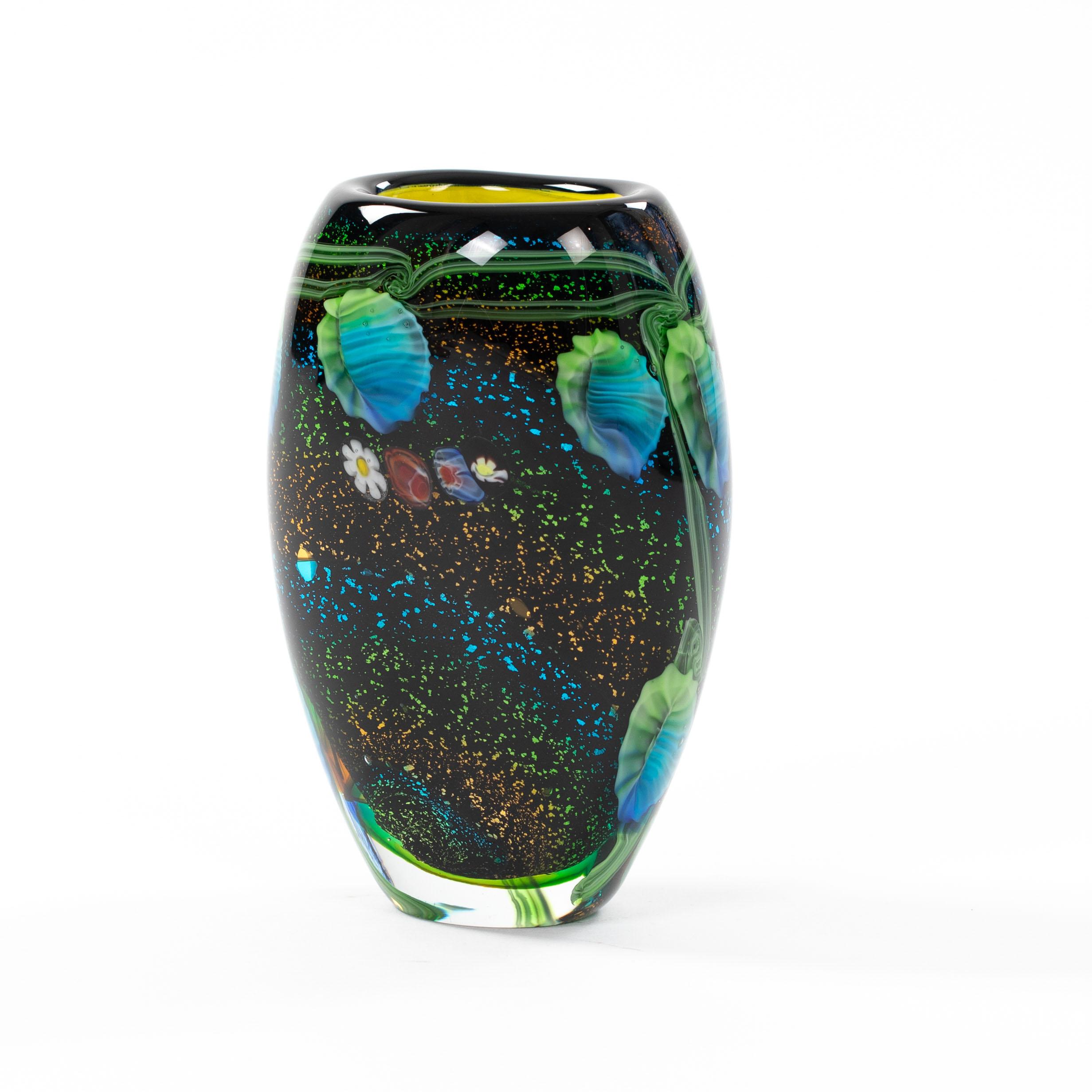 Piccolo vaso decorativo di Murano con murrine colorate

Il vaso eclettico ha una base ricoperta da piccole particelle colorate di vetro smerigliato semifuso sul nero, 
i grani hanno un carattere metallico e creano una superficie ruvida.
Il