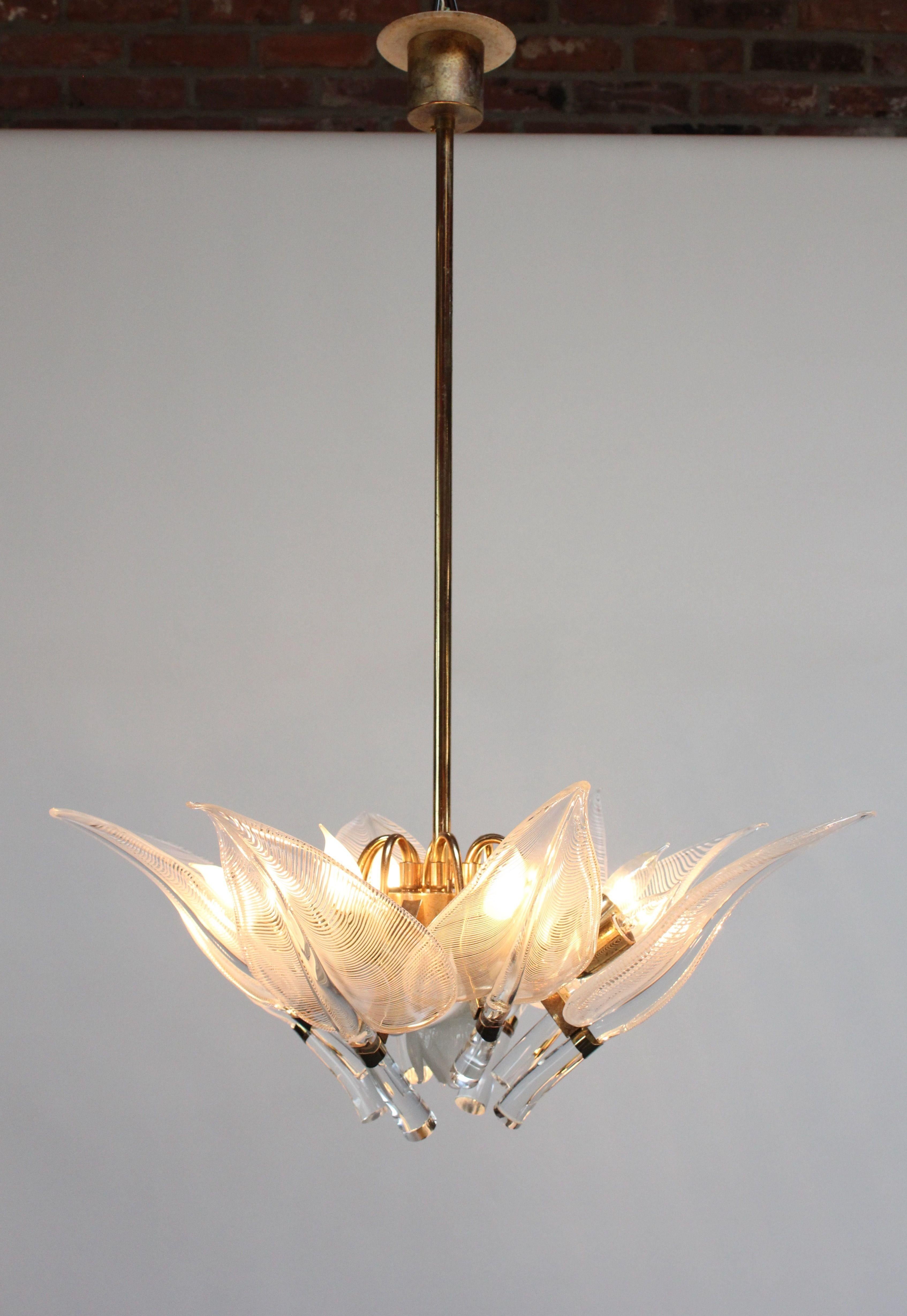 Elegant, luxe eight-fixture brass and blown glass 'lily leaf' form chandelier by Franco Luce for Murano (Italy, 1970s). Each blown glass leaf is transparent with a white filagree detail. The milk cased glass floral accent which mounts to the bottom