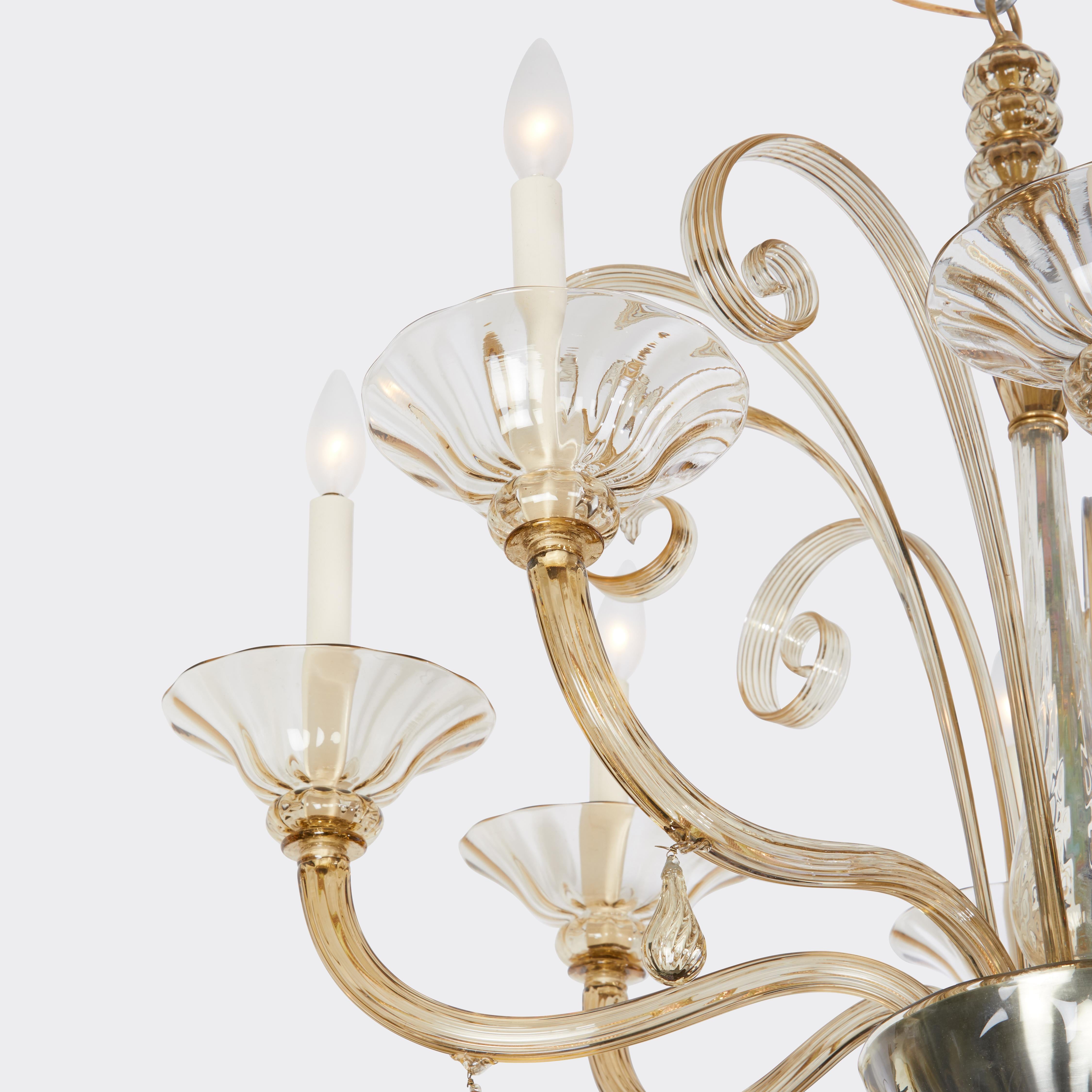 An Italian hand-blown pale amber Murano glass chandelier with eight arms issuing from the handblown dish center below a stem with cylindrical glass elements covering the stem. Each arm with tear drop shaped elements hanging, and bowl with glass drop