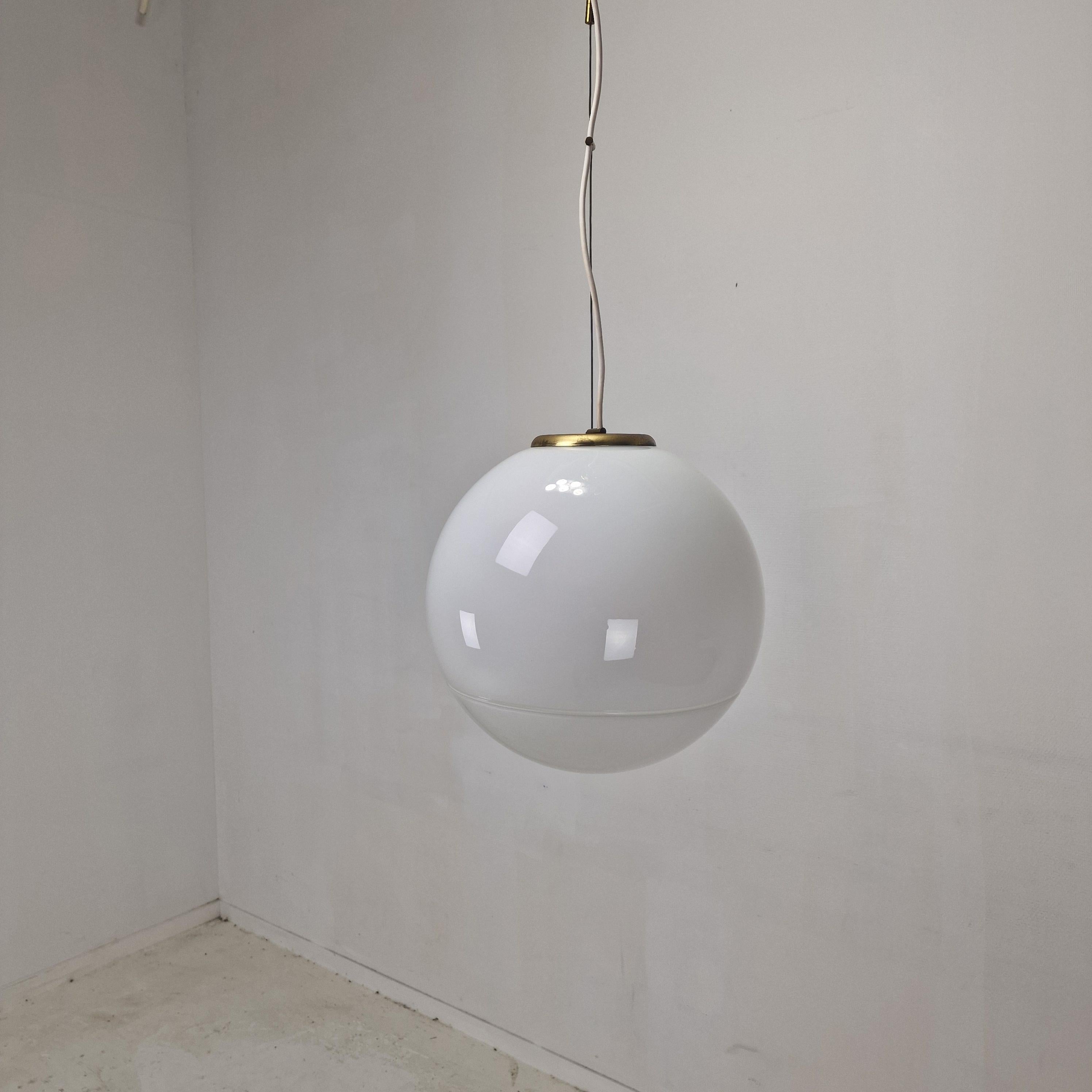 Una llamativa lámpara Globo Moderna de mediados de siglo, fabricada en Italia en la década de 1970.
Cristal de Murano soplado a mano suspendido de un elegante marco de latón. 
El globo está hecho de cristal opalino de Murano, que ofrece un
