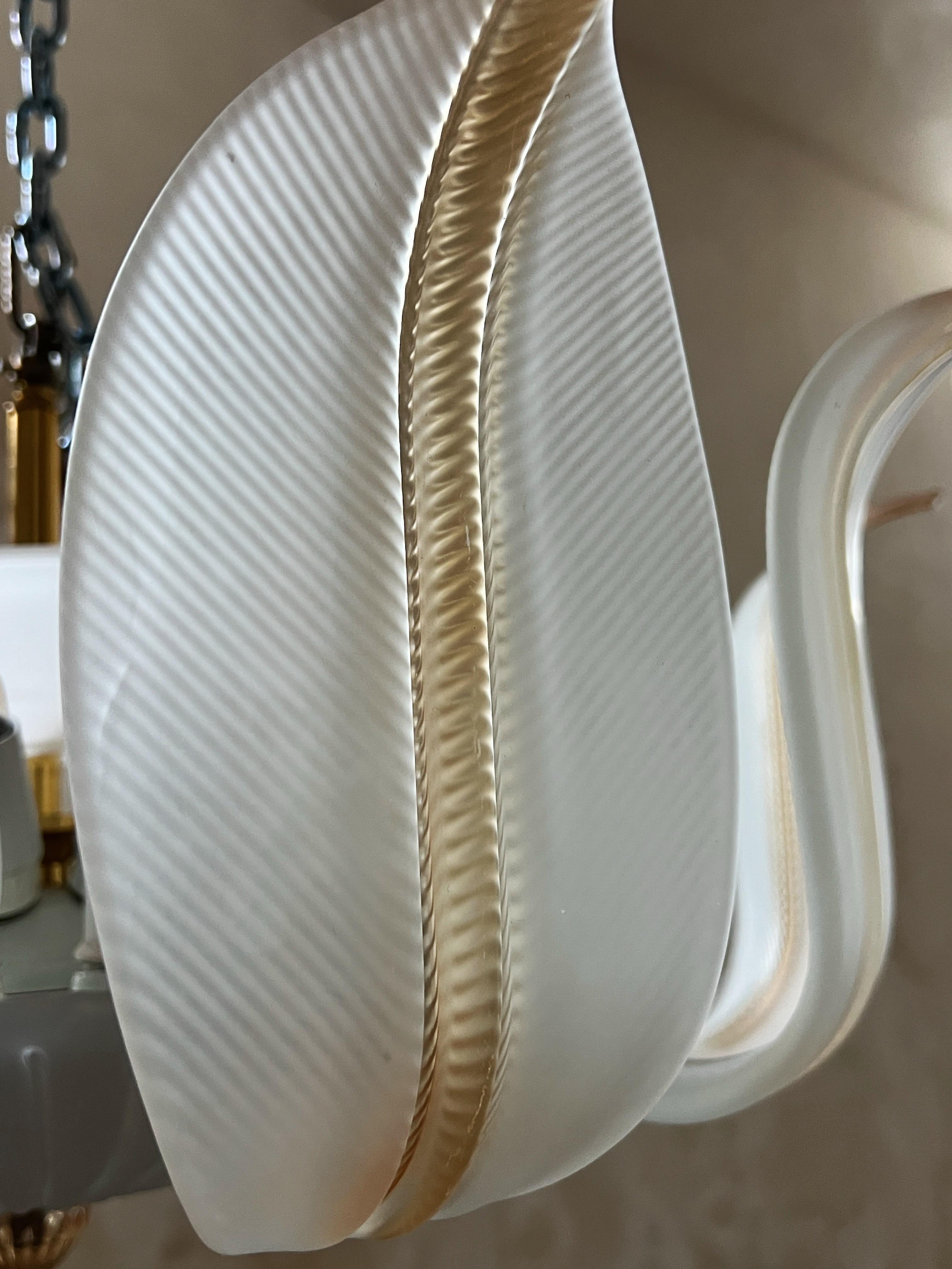 Un plafonnier raffiné en verre de Murano composé de feuilles de verre doucement translucides au ton blanc laiteux, chacune présentant un détail caramel chaud au centre.
Les feuilles forment une gracieuse composition circulaire qui crée une lumière