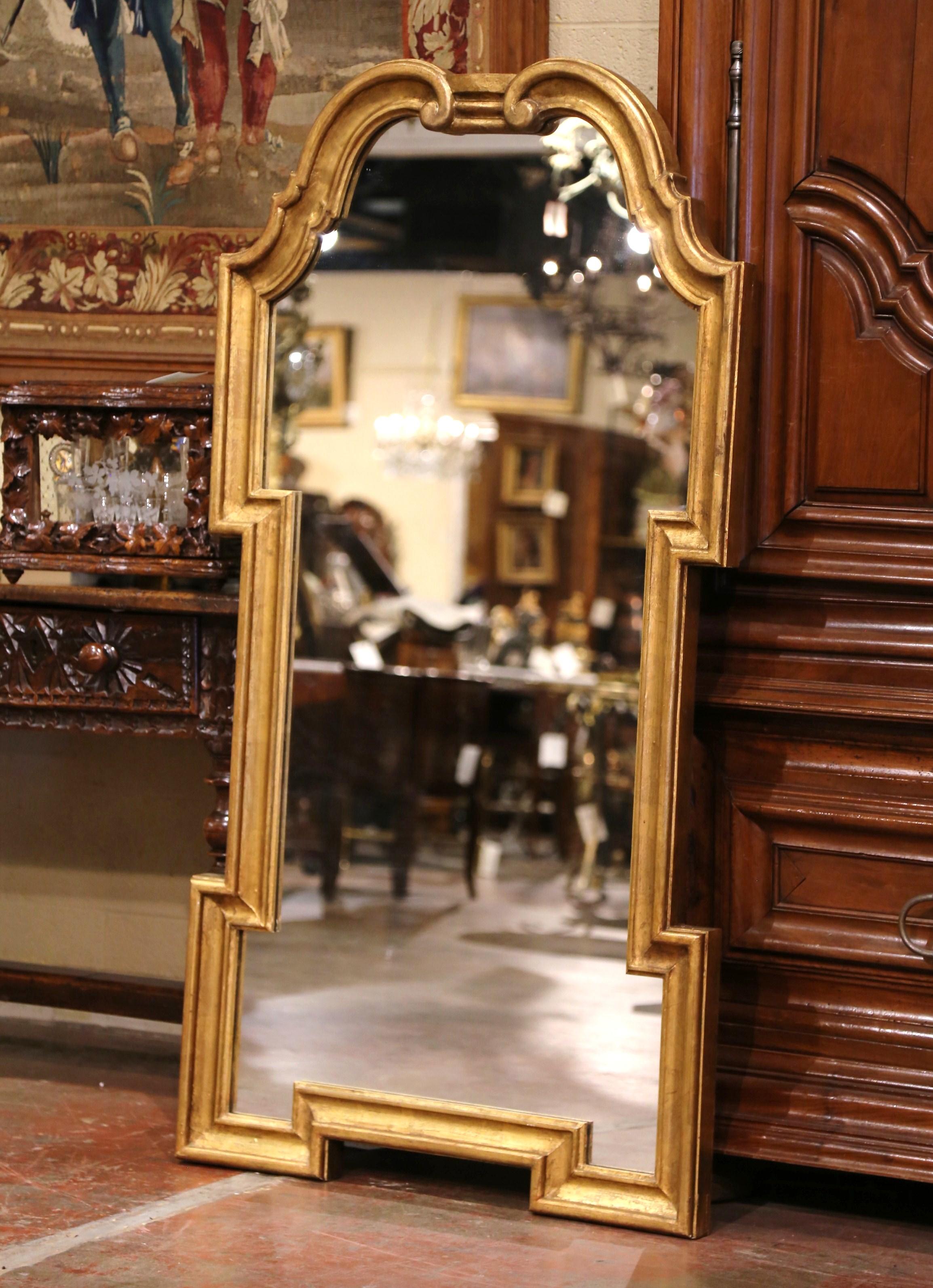 Dress a mantel with this elegant antique gilt wall mirror. Hand carved in Italy circa 1950, and almost 5 feet tall, the rectangular mirror features a double arched top over sides and bottom geometric motifs. The mirror is dressed with the original