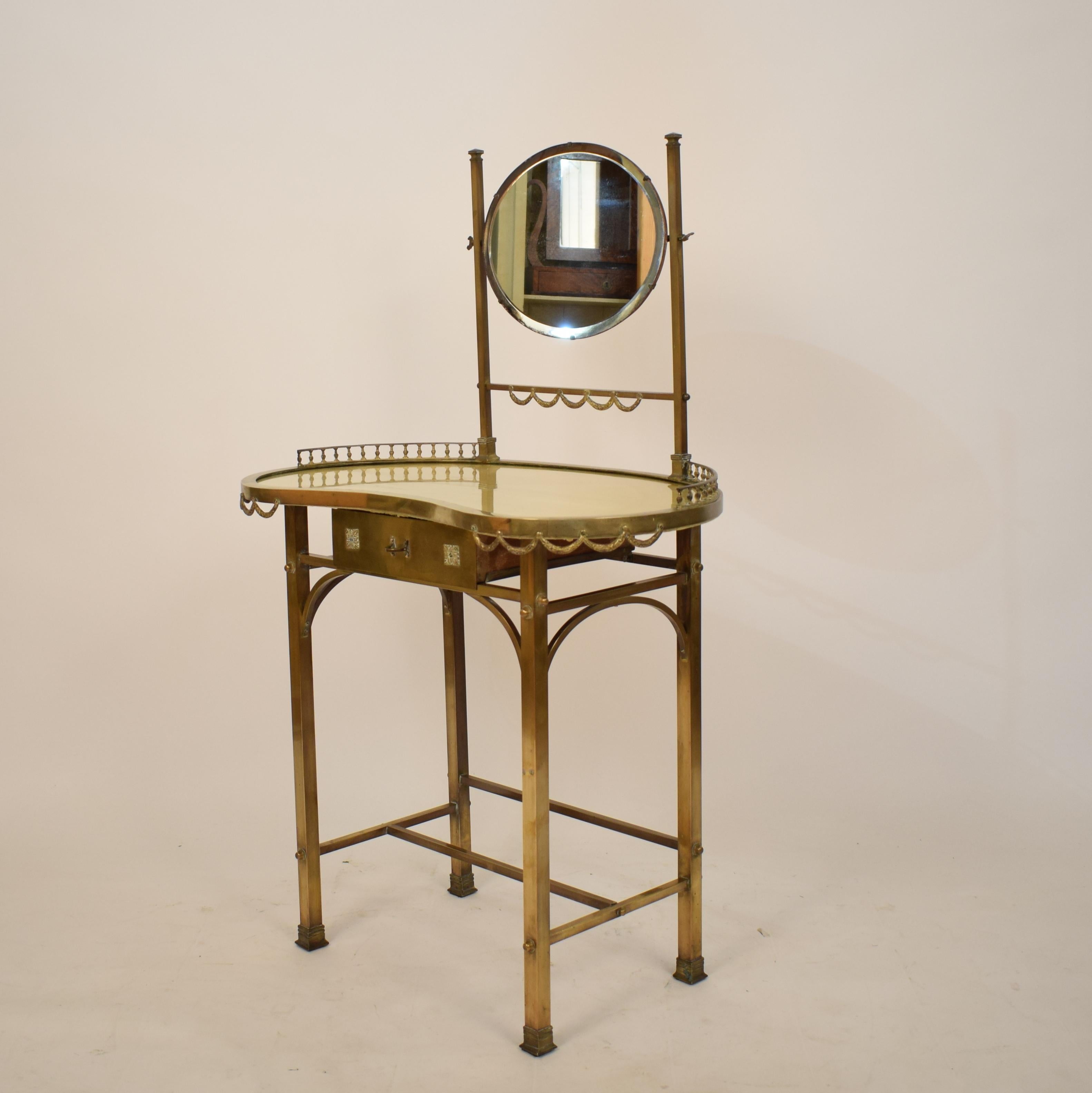 This beautiful and rare midcentury neoclassical style brass / mirrored dressing-table or vanity was made in Italy in the 1950s.
It is in original untouched beautiful condition. Even the golden silk underneath the glas top is there.
The brass