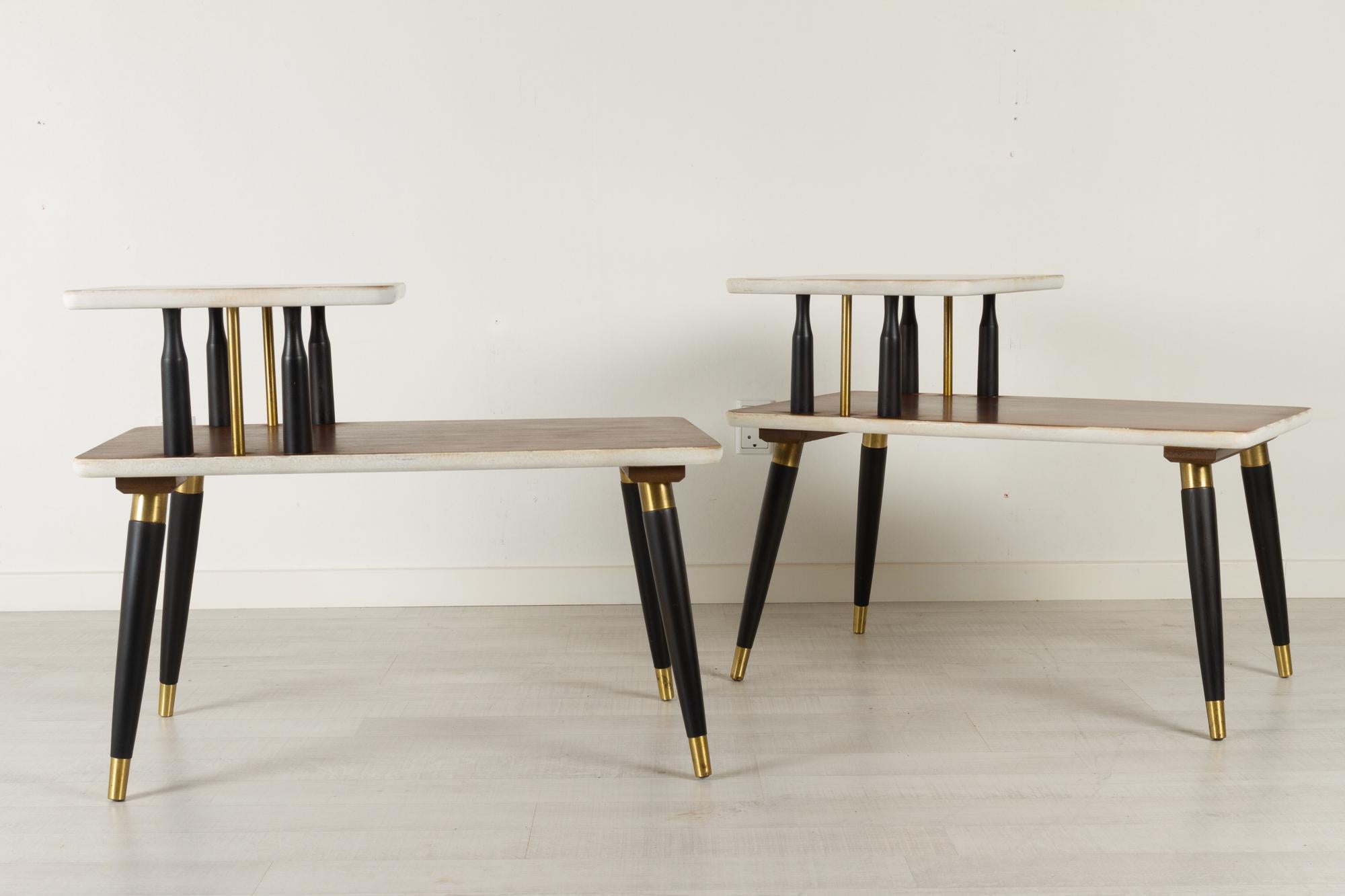 Vintage Mid-Century Modern Italian bedside tables 1960s, Set of 2.

Very elegant pair of tiered tables with teak tops and ebonized legs with brass details. Top tier resting on pillars of ebonized wood and brass rods. Round tapered legs with brass
