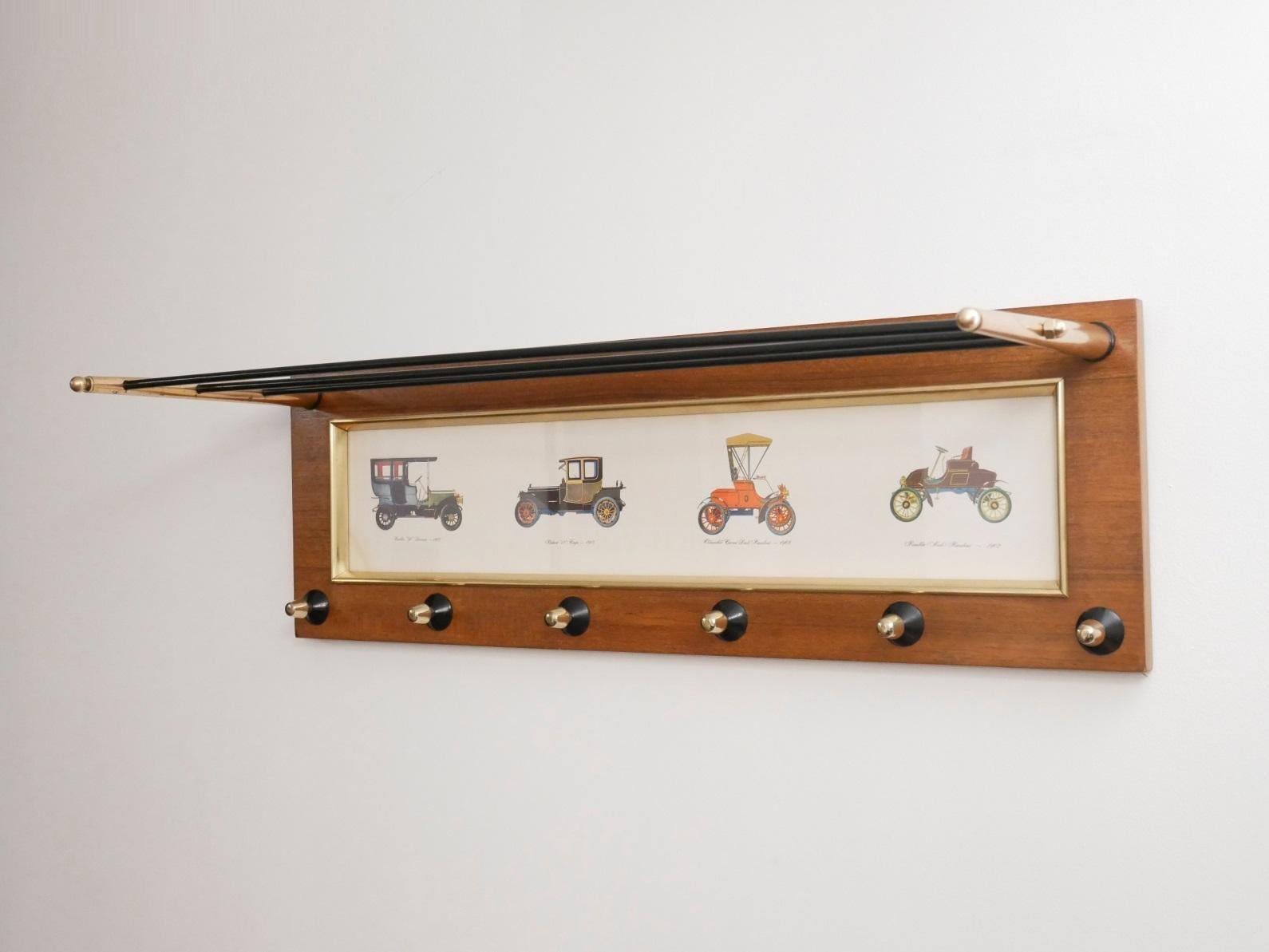 Midcentury Italian coatrack with a sleek design, teak wood frame matched with black metal painted hanger base and brass knobs. Oldsmobile lithography insert in the middle.