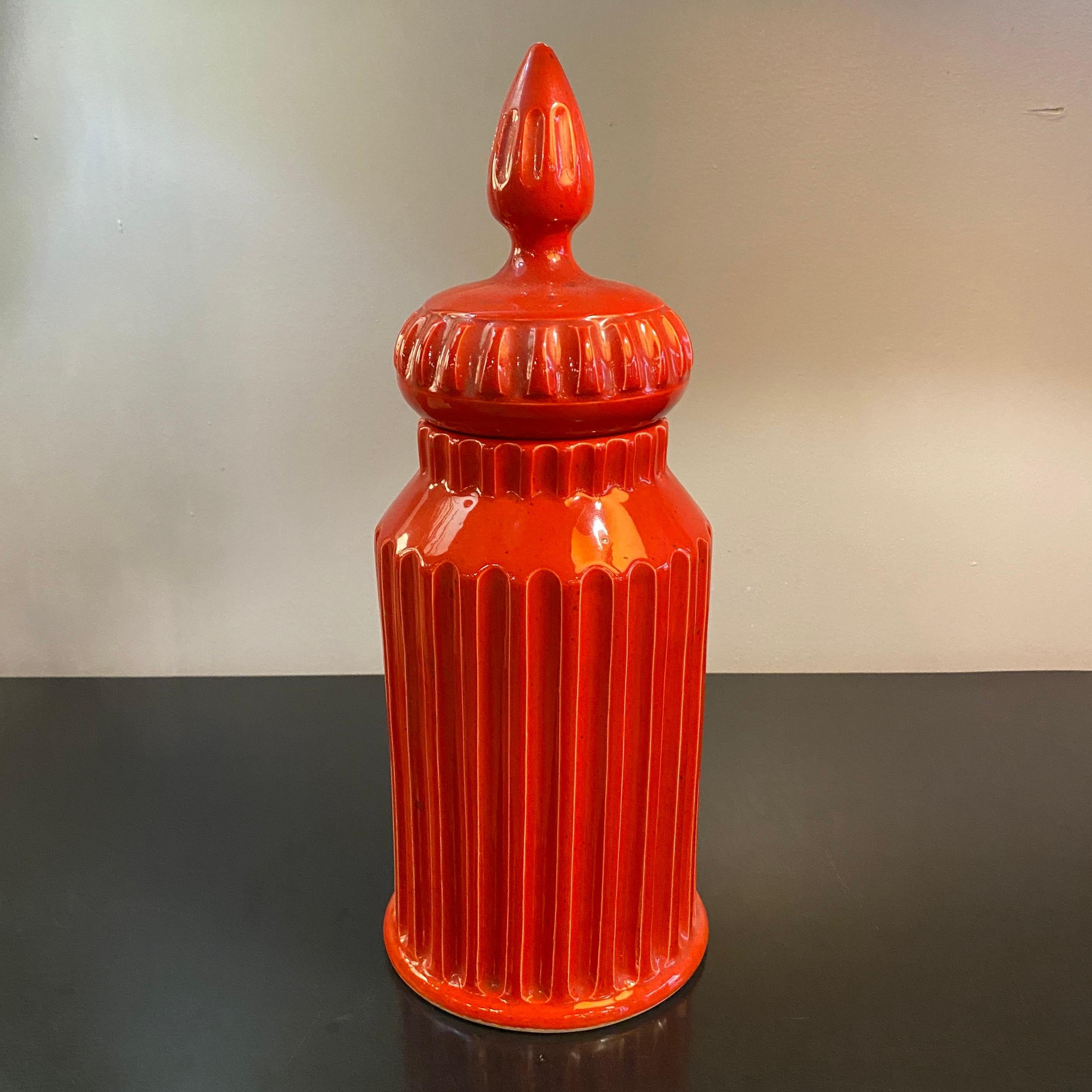 Mid-century, Italian, Moorish art pottery jar with lid in vibrant paprika red-orange. This glazed ceramic piece features a ribbed texture on both the jar and lid. Marked 