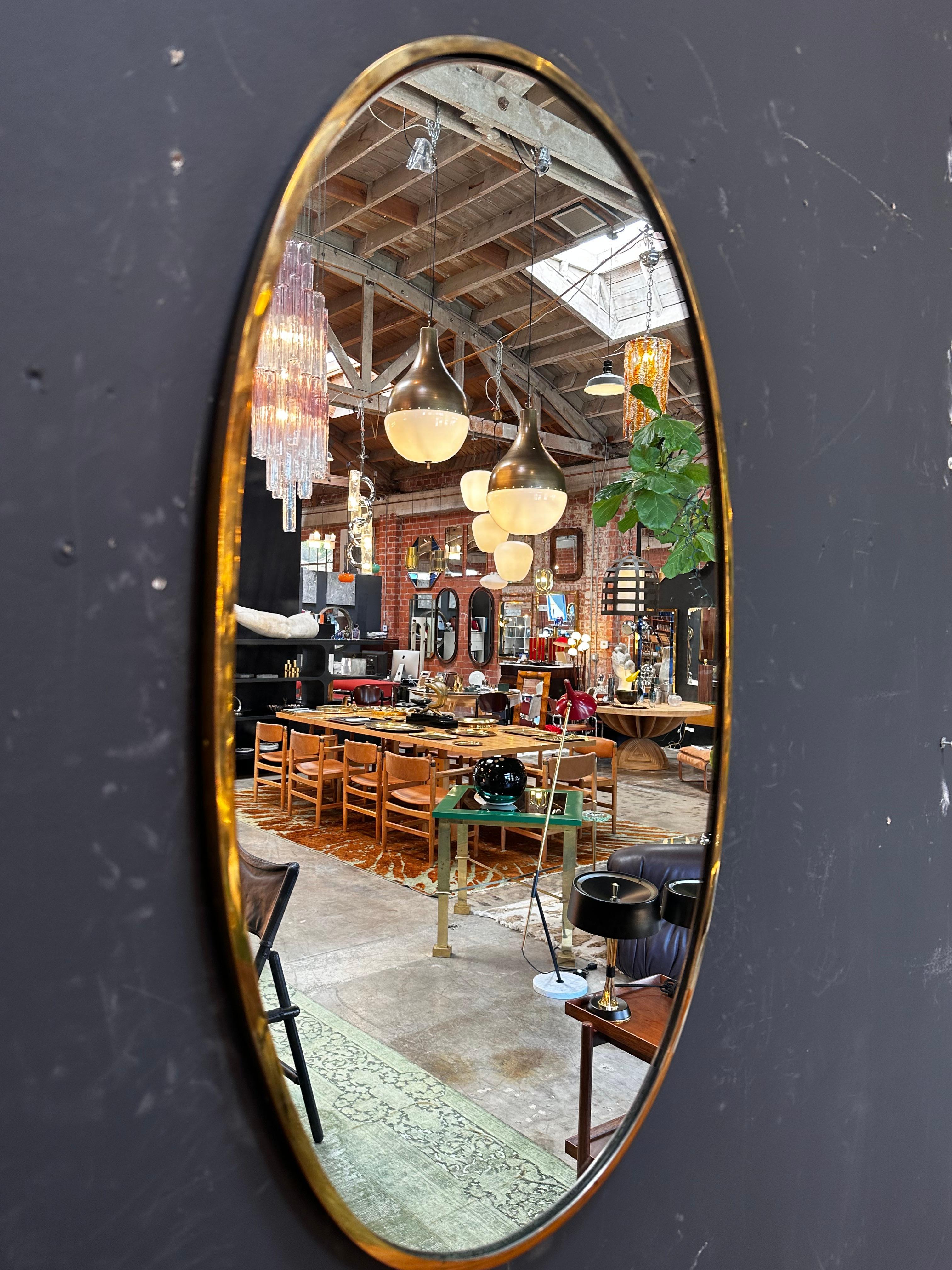 The Mid Century Italian Oval Brass Mirror from the 1980s features a chic oval shape and a timeless brass finish, embodying the style of the era.

