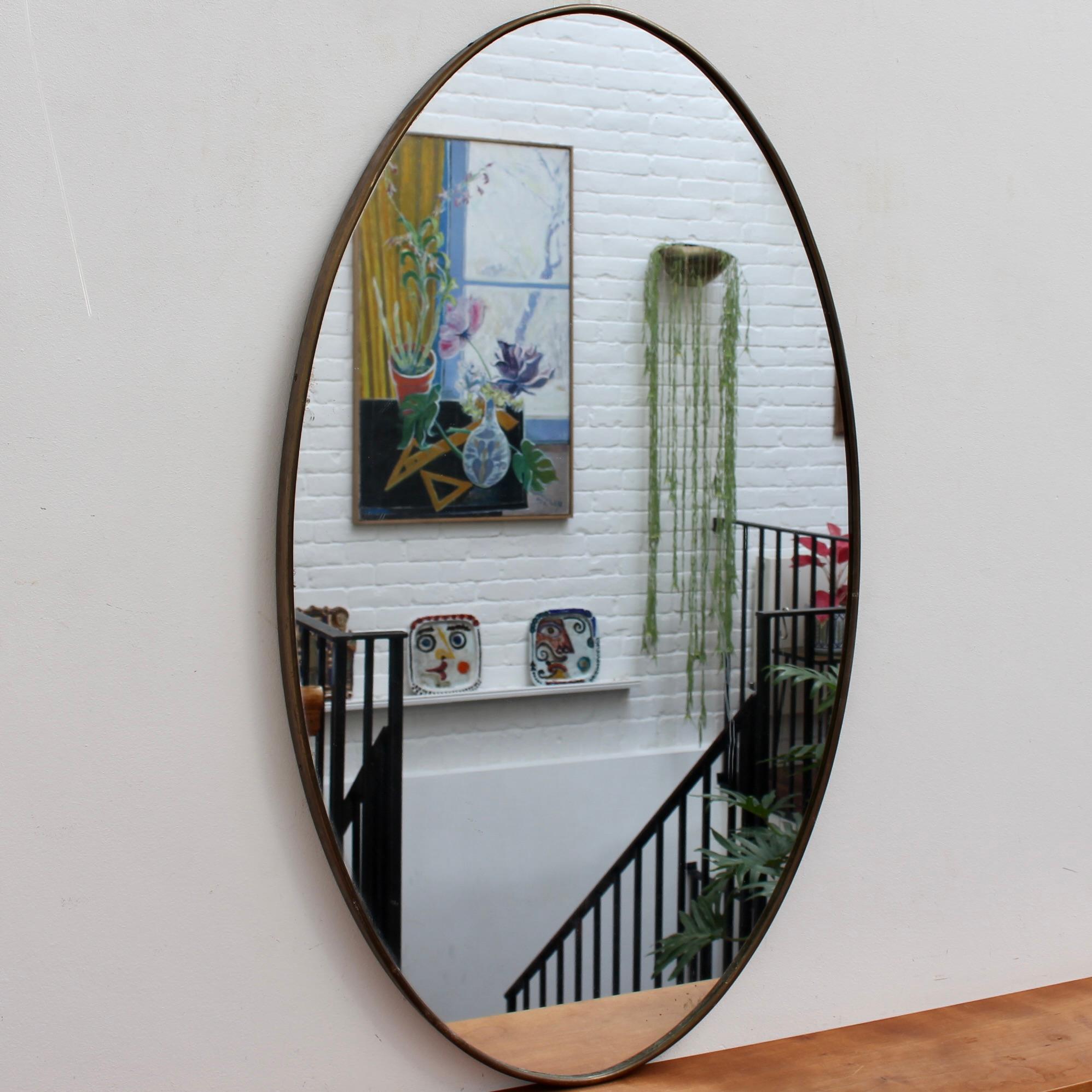 Mid-century Italian wall mirror with brass frame (circa 1950s). The mirror is oval in shape and very smart, with irresistible durability. The visual impression is characterful, elegant and very distinctive in a modern Gio Ponti style. The mirror is