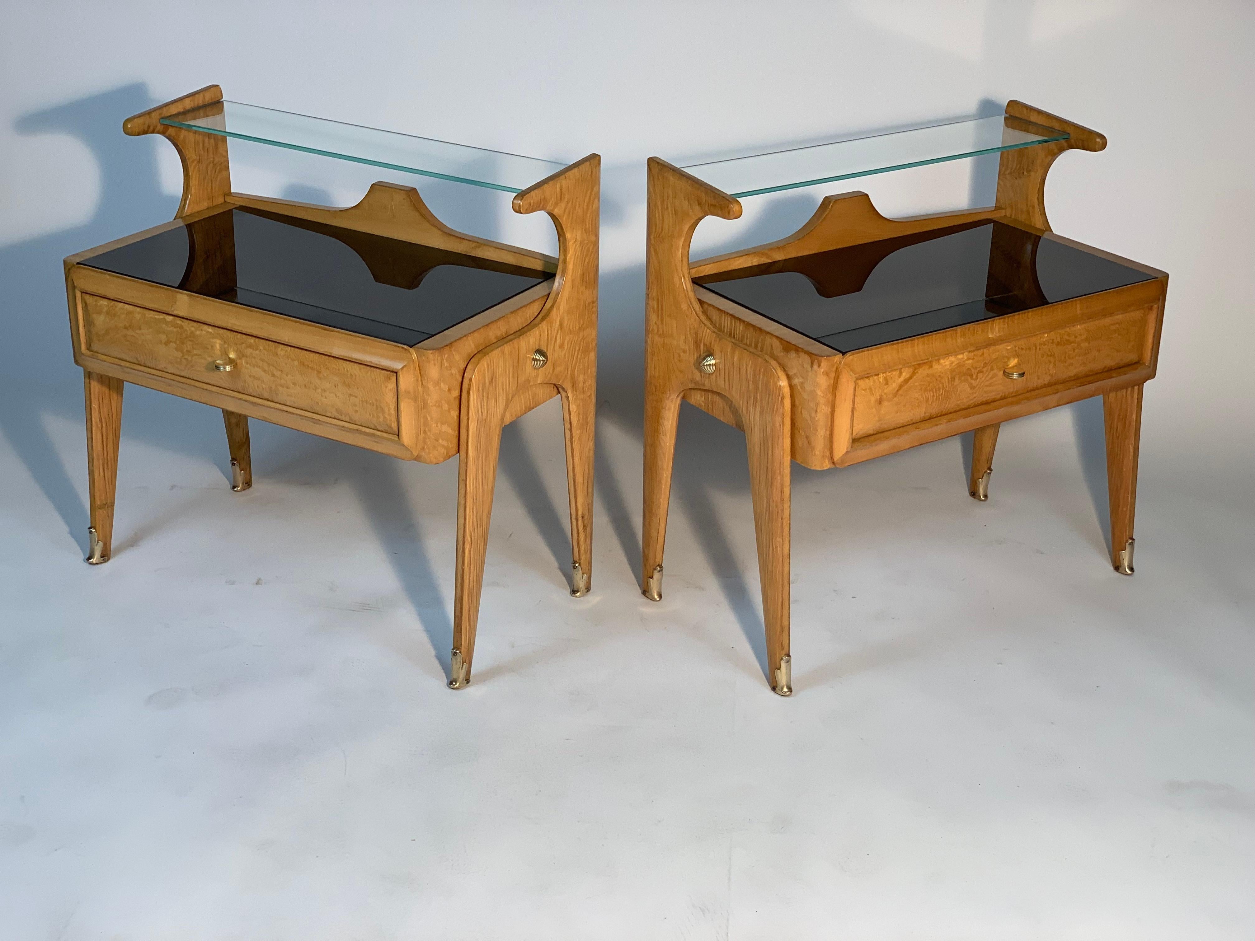 Pair of mid century bedside tables made by the Milanese firm Dassi Lissone Milano in precious and luxurious light wood.
The side legs, all in a single shaped piece, continue upwards to support a ground glass top.
The lower top is in black glass