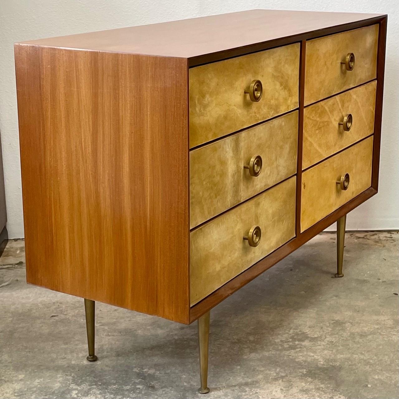 Cassettone a sei cassetti con frontali in pergamena, gambe e maniglie in ottone, in una cassa in mogano a nastro. Elegante e leggera, questa cassapanca è un accento delizioso per qualsiasi stanza.