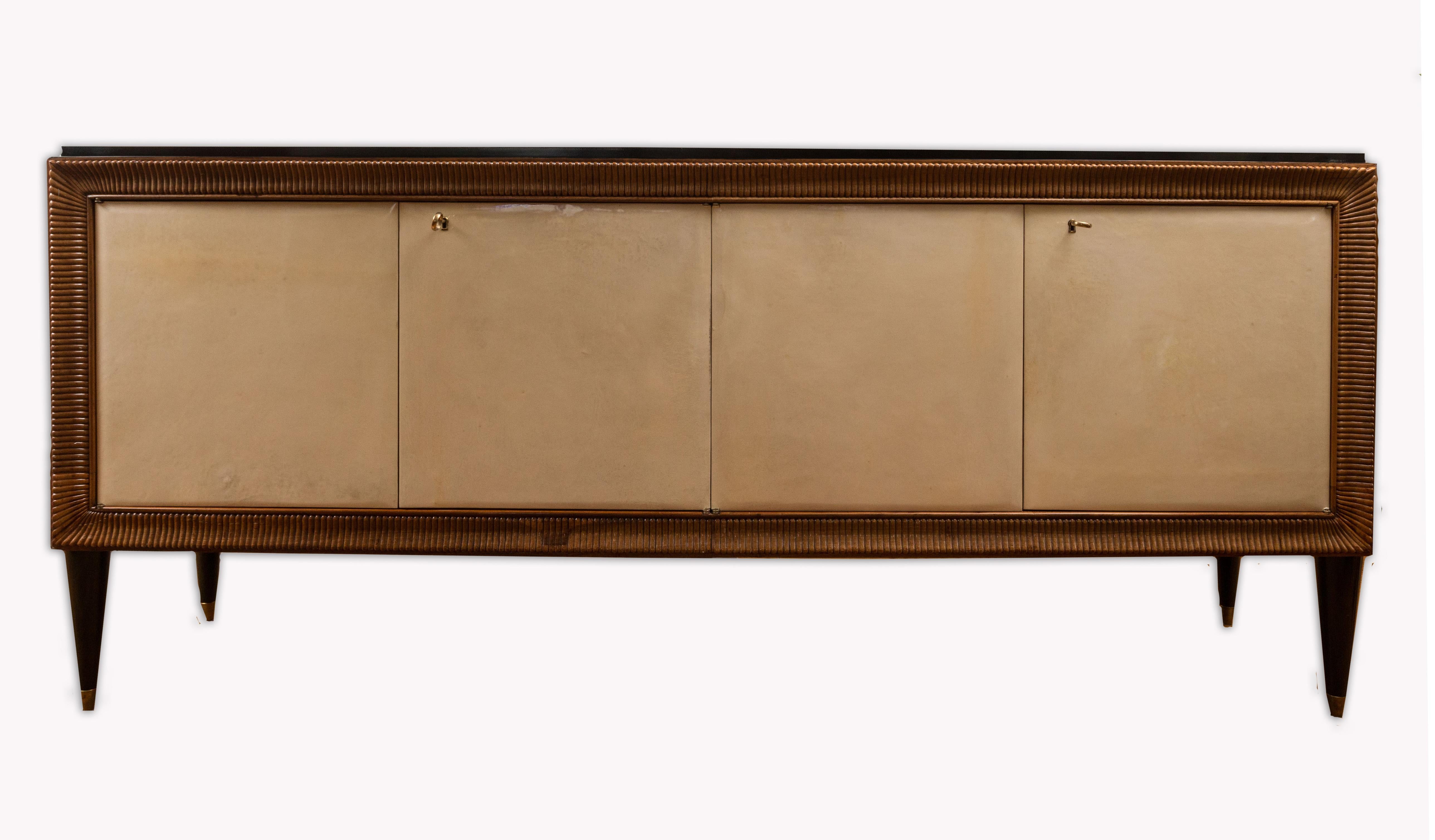 Eine wunderbare italienische Anrichte im modernisierten Deco-Stil mit einem schwarz lackierten, abgestuften Plateau über vier Pergamenttüren, die von  mit einem Rahmen aus geriffeltem Nussbaumholz und einem Abschluss auf abgerundeten und konisch