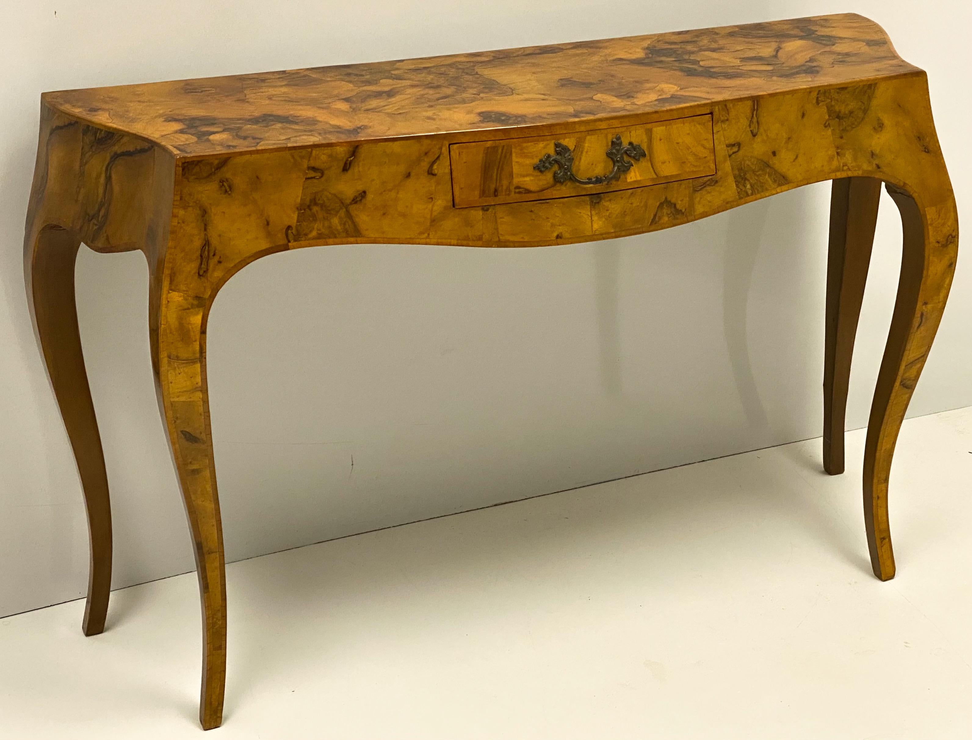 This is an Italian patchwork burl serpentine console table. It has a small, paper lined single drawer with original brass hardware. It is unmarked and in very good condition. The top surface measures:
50” L x 15” W.