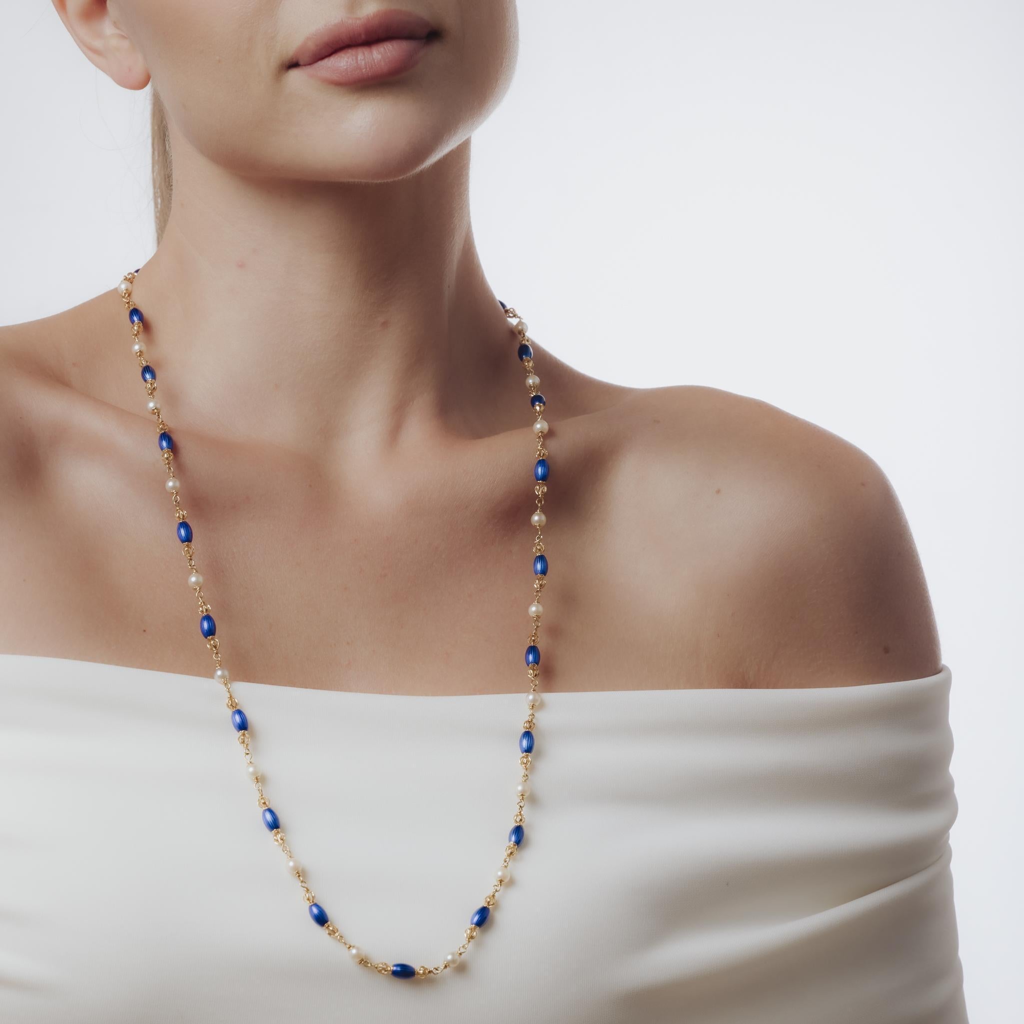 Ce collier italien du milieu du siècle dernier, datant des années 1960, est réalisé en or jaune 18 carats avec de riches accents d'émail bleu. Mesurant 29 pouces de long, il est orné de perles lustrées d'environ 5,14 mm, qui ajoutent une douce