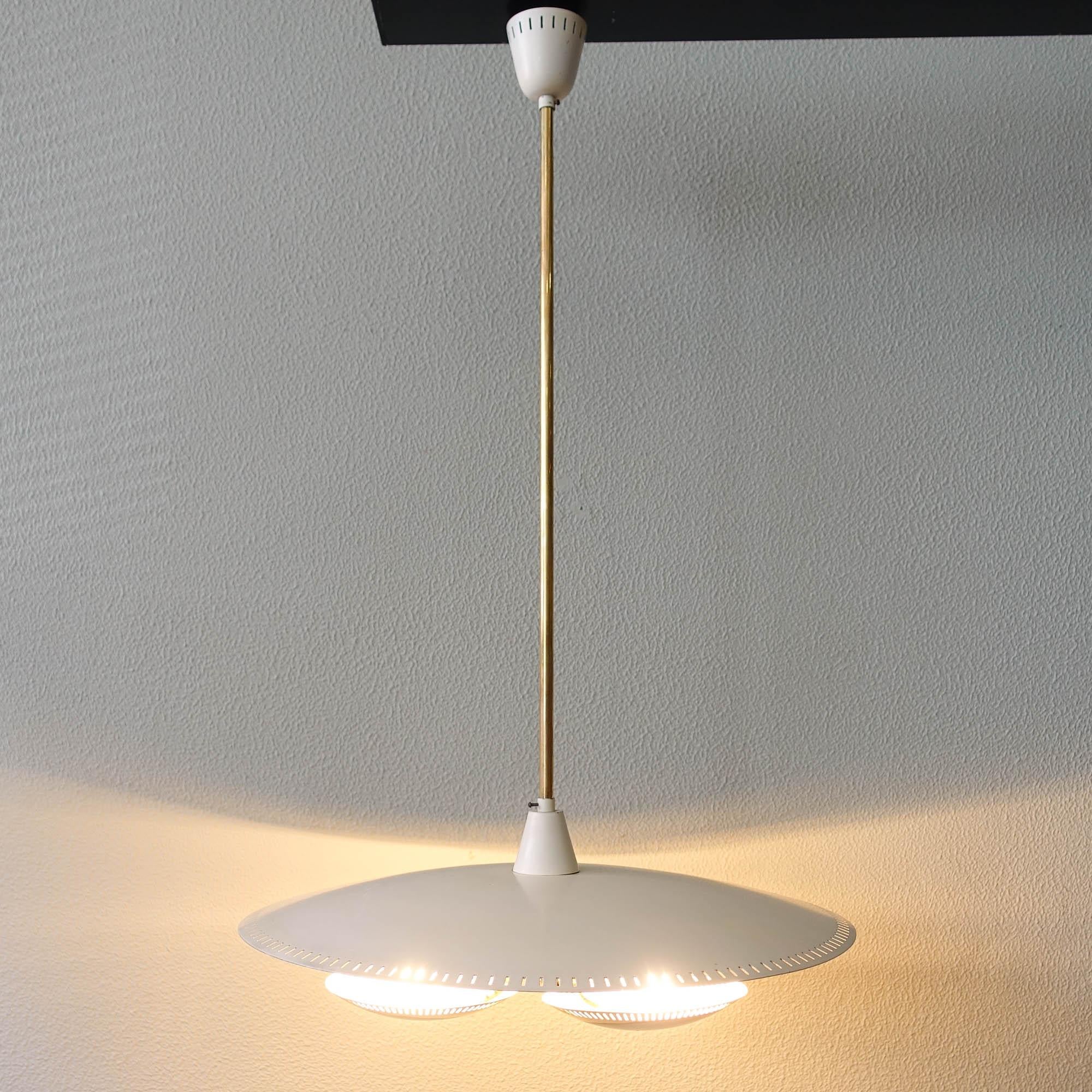 This pendant lamp was designed and produced in Italy, during the 1950's. The design is reminiscent of the Gino Sarfatti for Arteluce lamps, or even Stilnovo.
It features a large ivory plate with perforated edges, and below, hold by three brass