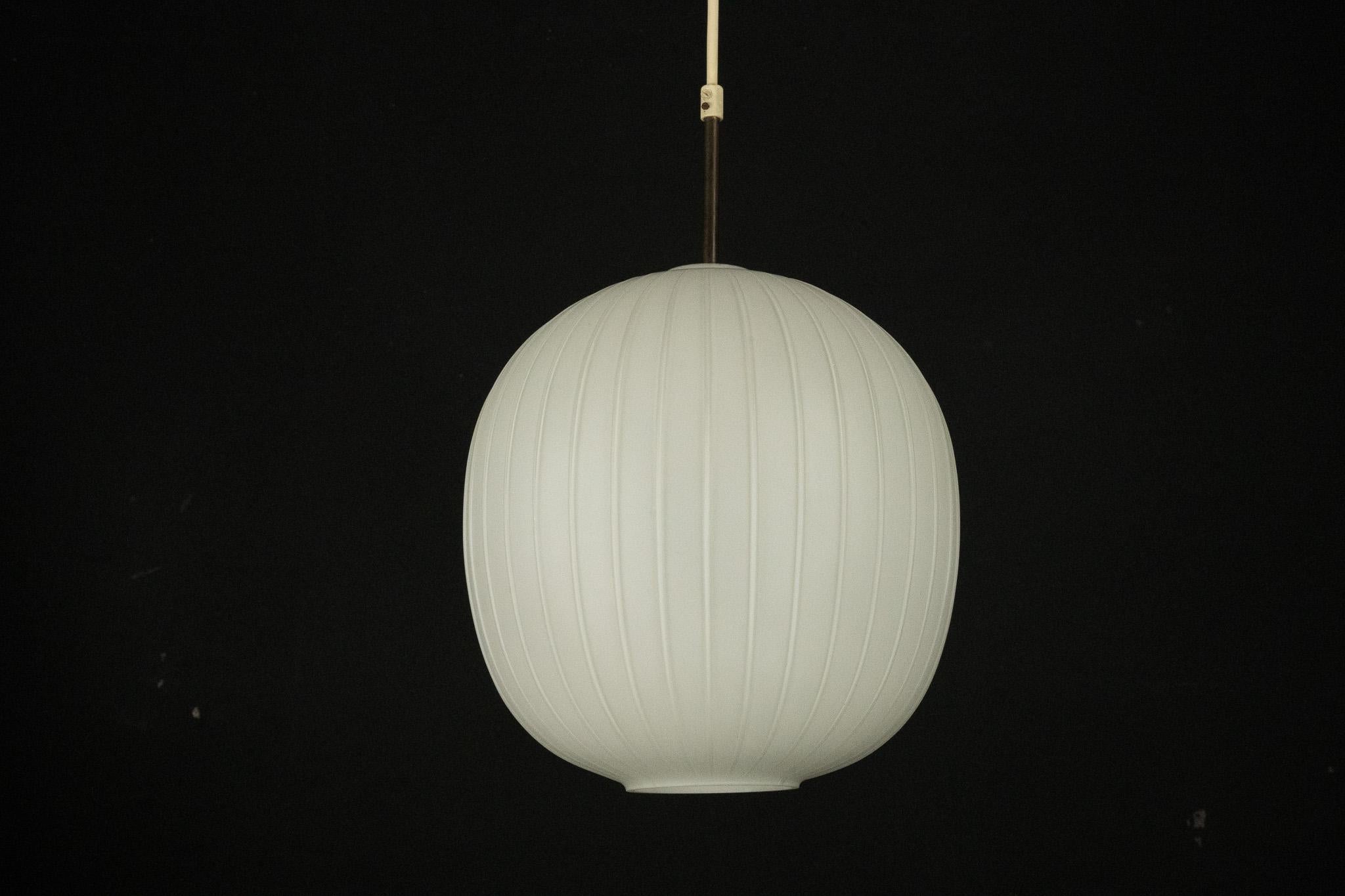 A refined Mid-Century Modern pendant light, in the manner of the iconic designs of Arredoluce Monza, crafted in Italy during the 1950s. This elegant fixture features a smooth opaline glass sphere and brass elements that showcase their original