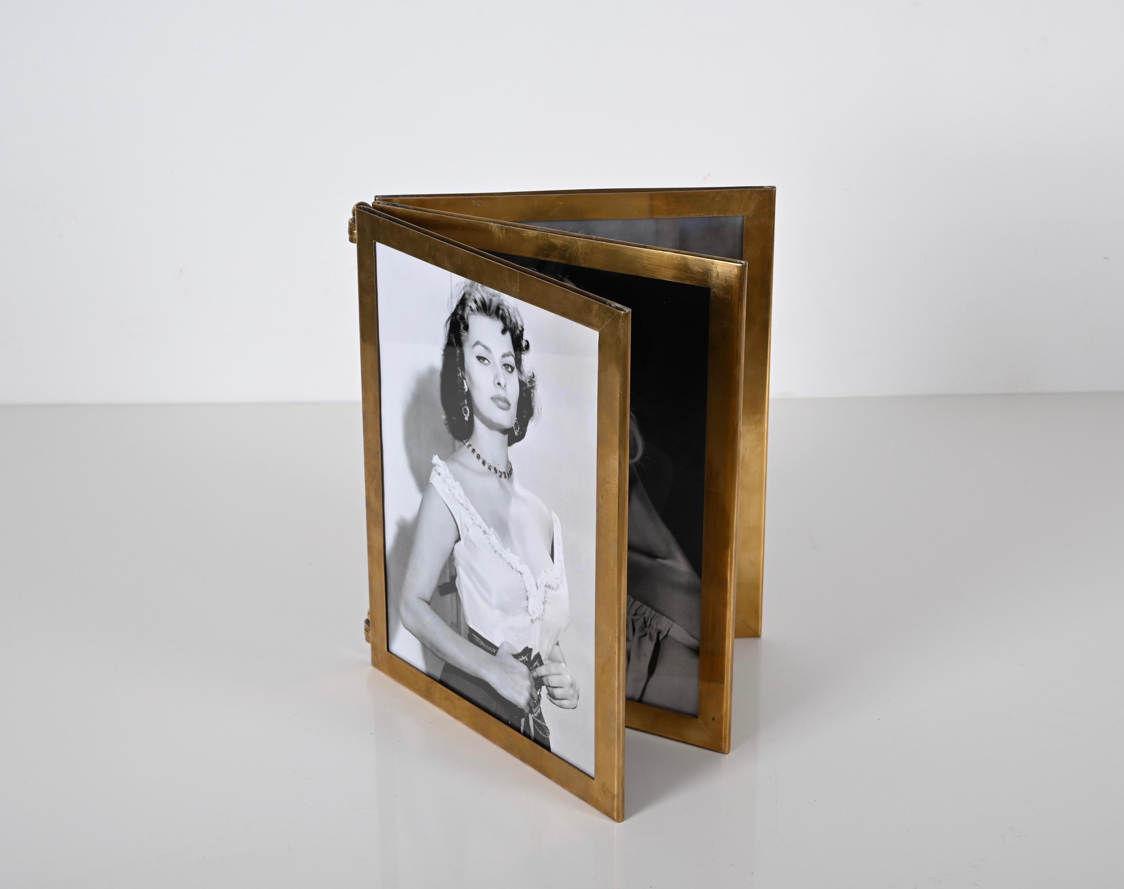 Marvellous Italian picture frame in the shape of a book fully made in solid brass. This outsanding Hollywood Regency piece was made in Italy in the 1950s.

This finely crafted photo frame recalls the the shape of a book and can hold 6 photos.  Fully