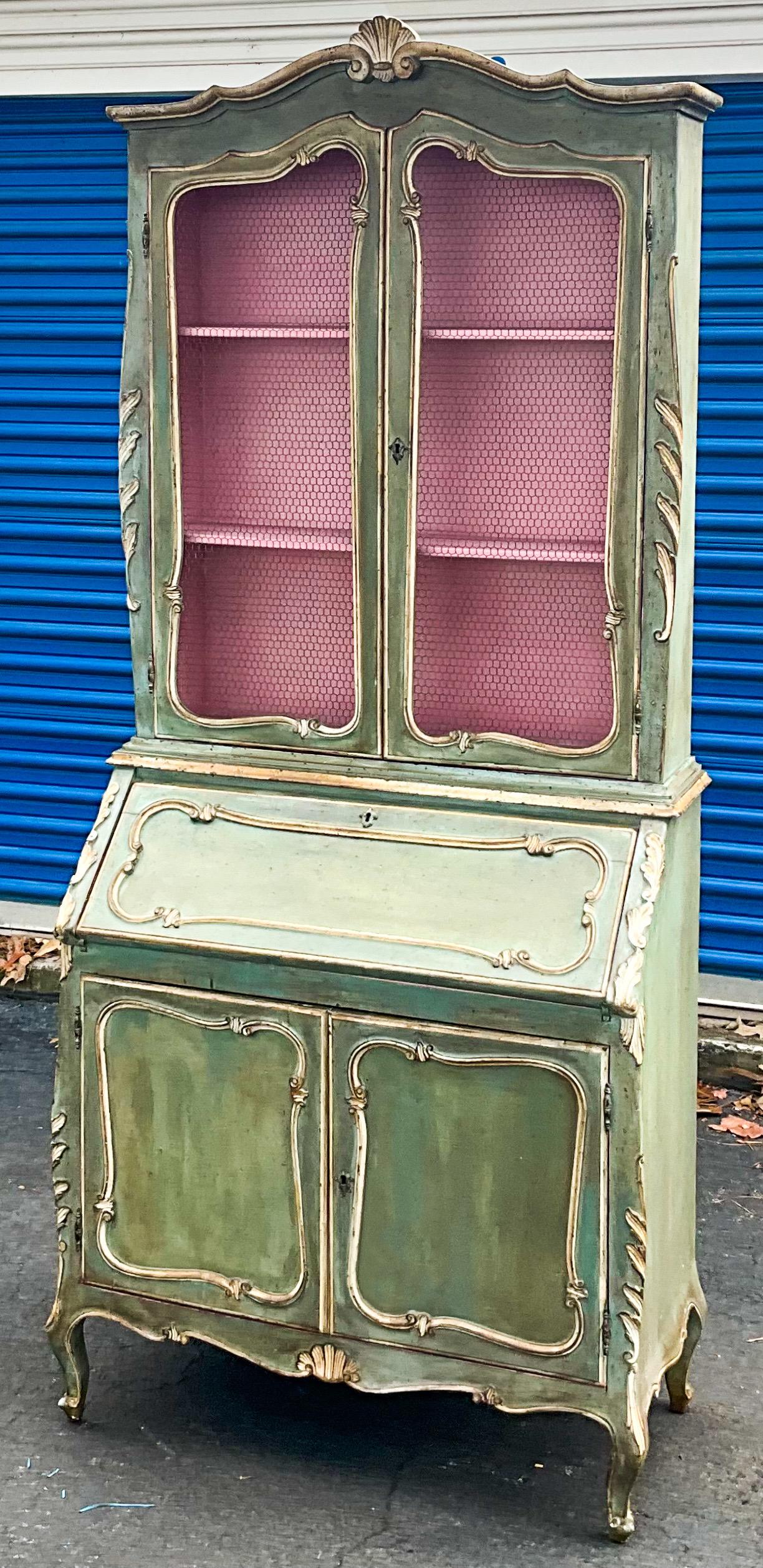 This is a lovely mid-century hand painted Italian Secretary with French styling. The top is 8”W. The interior is pink, and the wire front doors are in very good condition. The exterior is green with ivory accents. It is unmarked and in very good